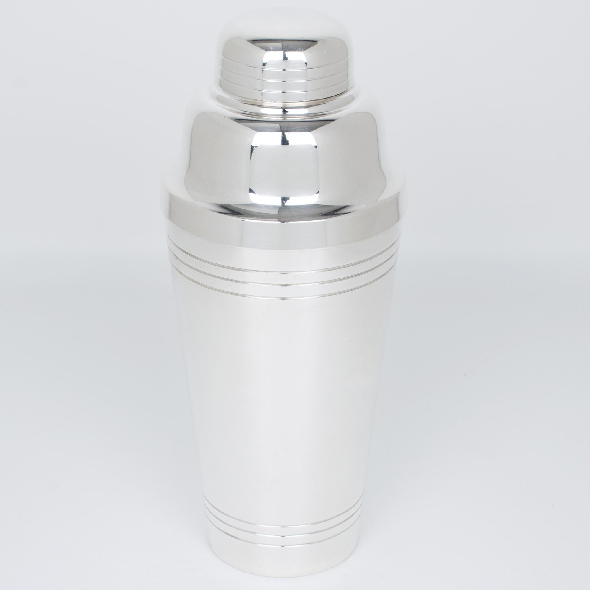 Esta elegante coctelera cilíndrica Art Déco de plata fue fabricada por el orfebre francés Roux & Marquiand, en París, en la década de 1940. Esta coctelera grande y alta de tres secciones tiene un tapón extraíble y un filtro colador. Este accesorio