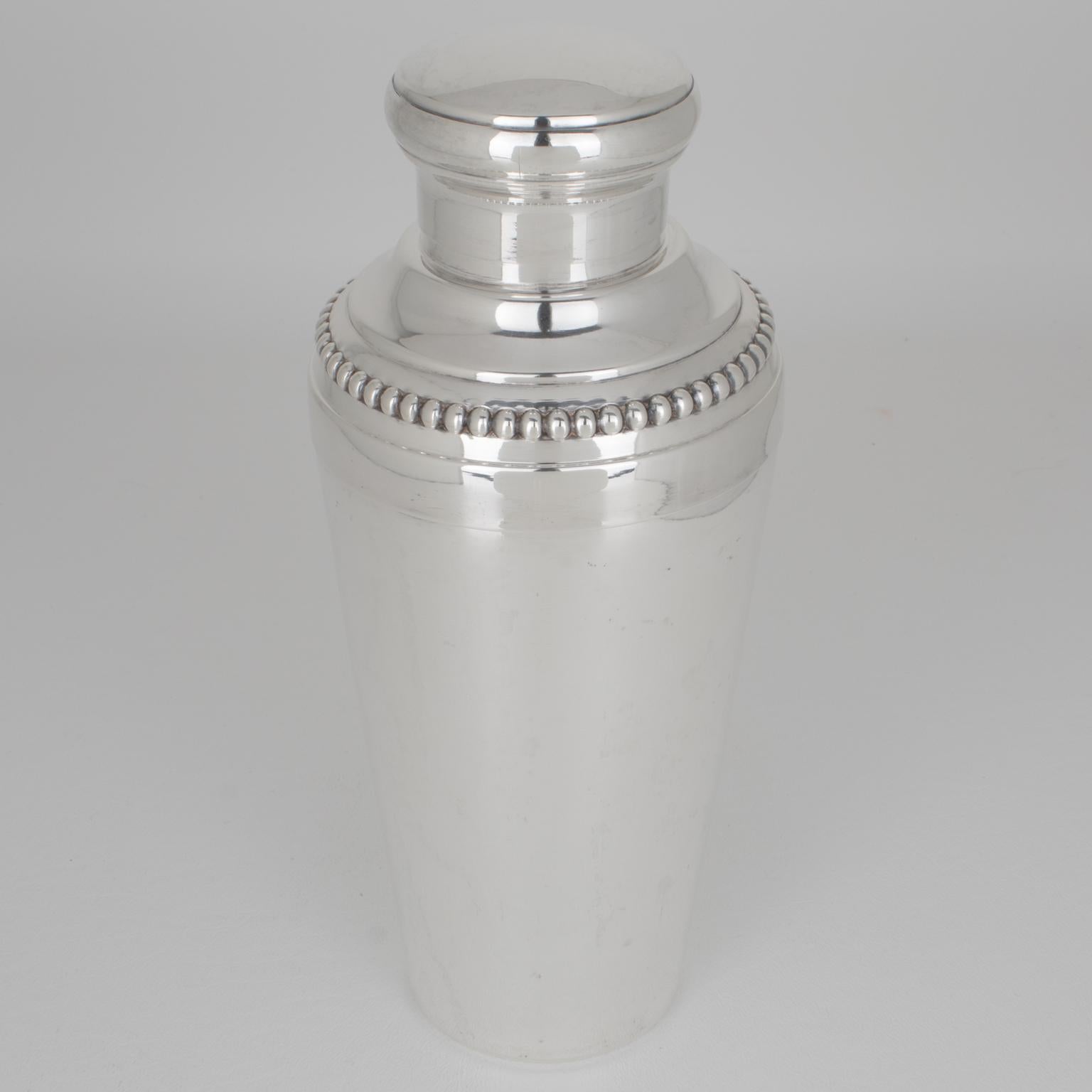 Esta impresionante coctelera cilíndrica francesa Art Déco de plata fue fabricada por el platero Louis Pechard en París, hacia 1940. La coctelera de tres secciones tiene un tapón extraíble y un filtro colador. La pieza tiene una bella forma