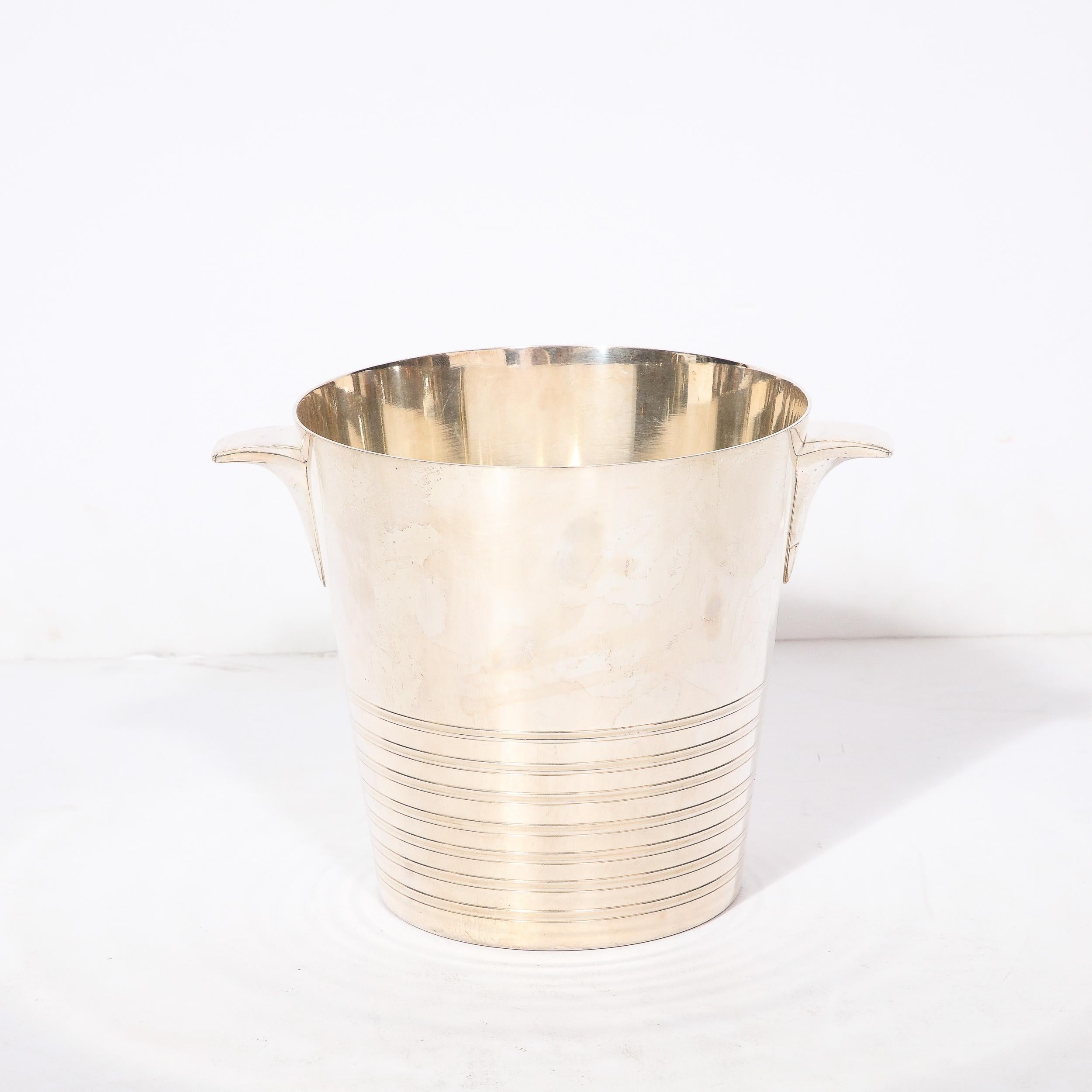 This unique Art Deco Silver Plate Ice Bucket originates from France, Circa 1930. Featuring curved handles that create and elegant swooping silhouette extending outwards from the body of the piece, which on the lower third has precise and radiant
