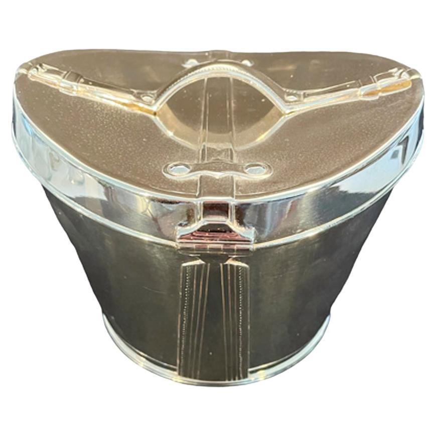 Whimsical Art Deco silver plate biscuit box in the form of a Victorian leather top hat box, of ovoid form with raised ends and applied strap handle and having simulated stitching and hinged closure. Thumbnuts inside the lid allow the handle to be