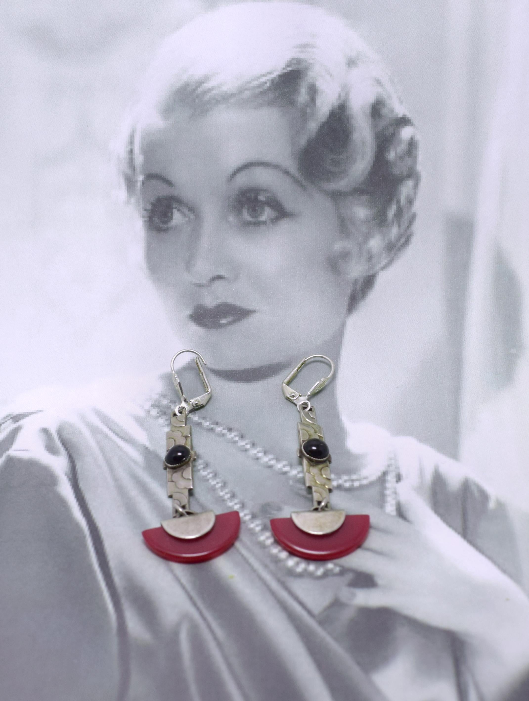 Beautiful piece of Art Deco jewellery dating to the 1930's. These earrings are an absolute delight and any lady of style will love them.  Made from black glass and red bakelite with silver plated back panel with a wonderful clouds embossed in a
