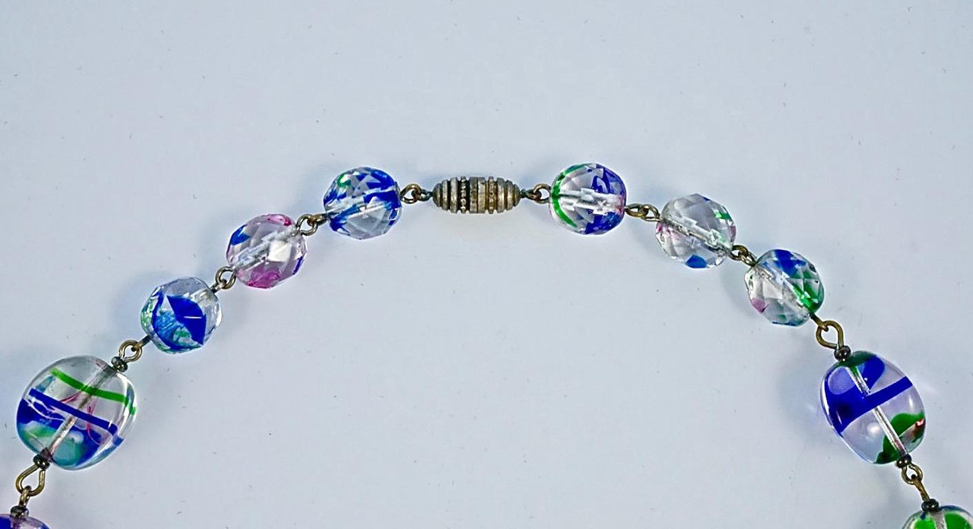 Collier Art Déco en plaqué argent avec des perles en verre iris rose, bleu et vert et un fermoir barillet. Il y a trois perles à facettes de chaque côté du fermoir, et les perles principales ont une forme lisse inhabituelle. Longueur 46cm / 18