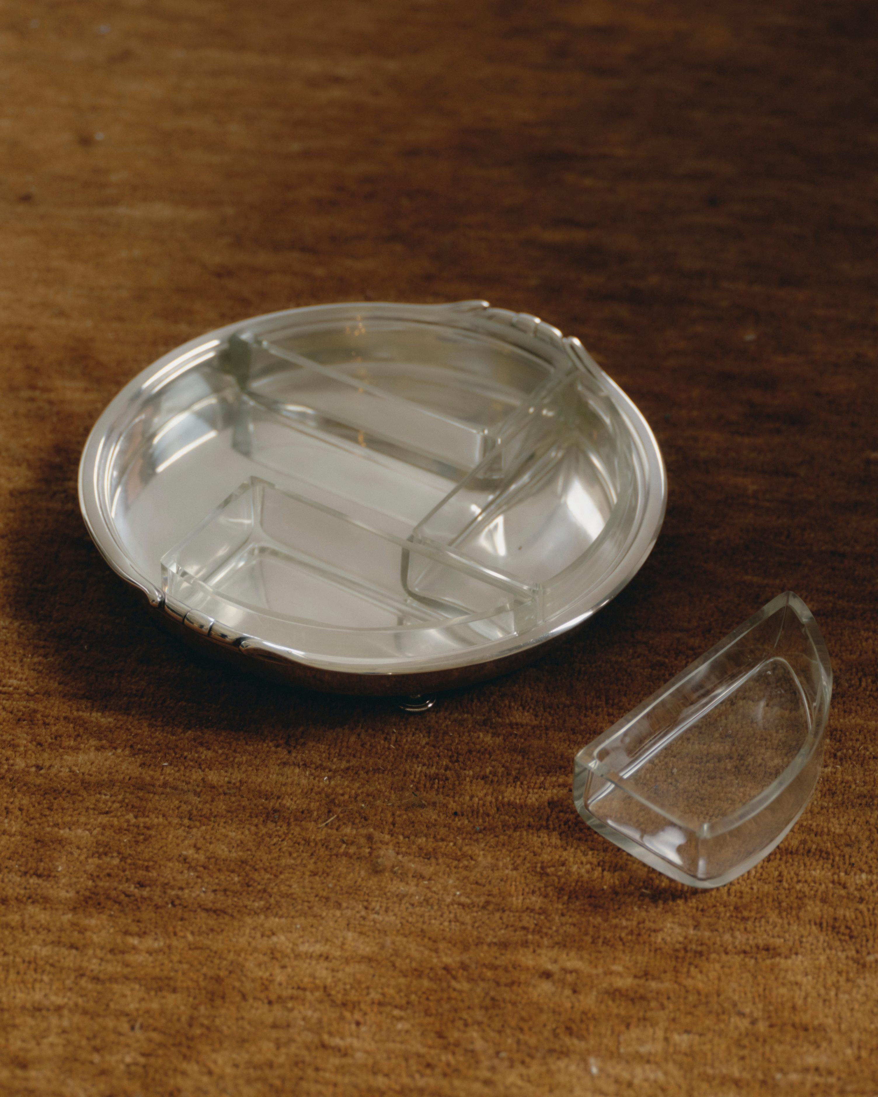 Runde Schale mit vier herausnehmbaren Fächern aus gegossenem Glas, auf versilbertem Metallsockel mit drei Kugelfüßen. Klare Linien und ausgewogene Geometrie sind charakteristisch für den Art déco-Stil. Europäische Arbeiten aus den 1930er