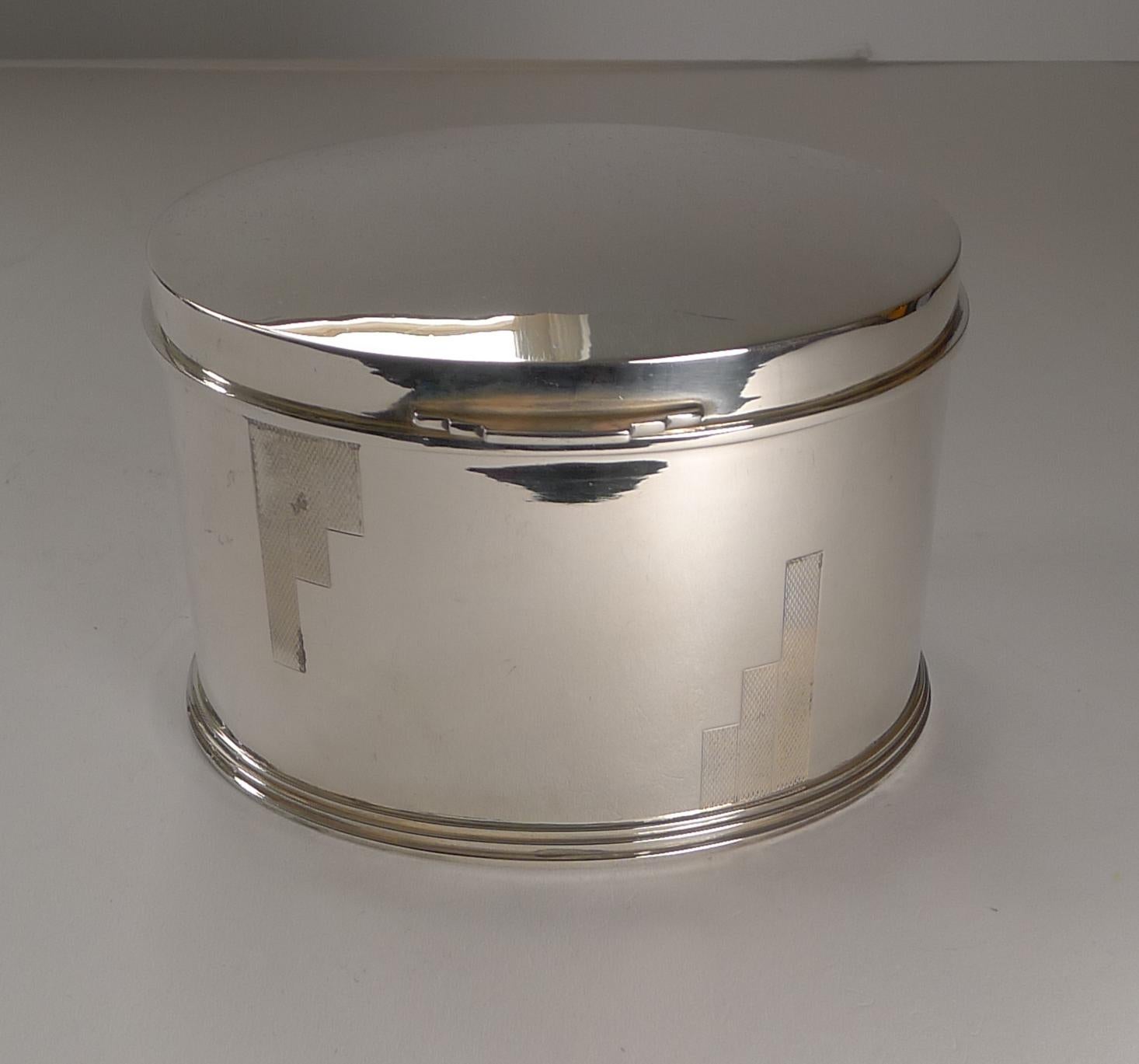 Just returned from our silversmith's workshop where it has been professionally cleaned and polished, restoring it to it's former glory.

The oval box has an engine turned geometric design to both front and back; the lift to the front is also