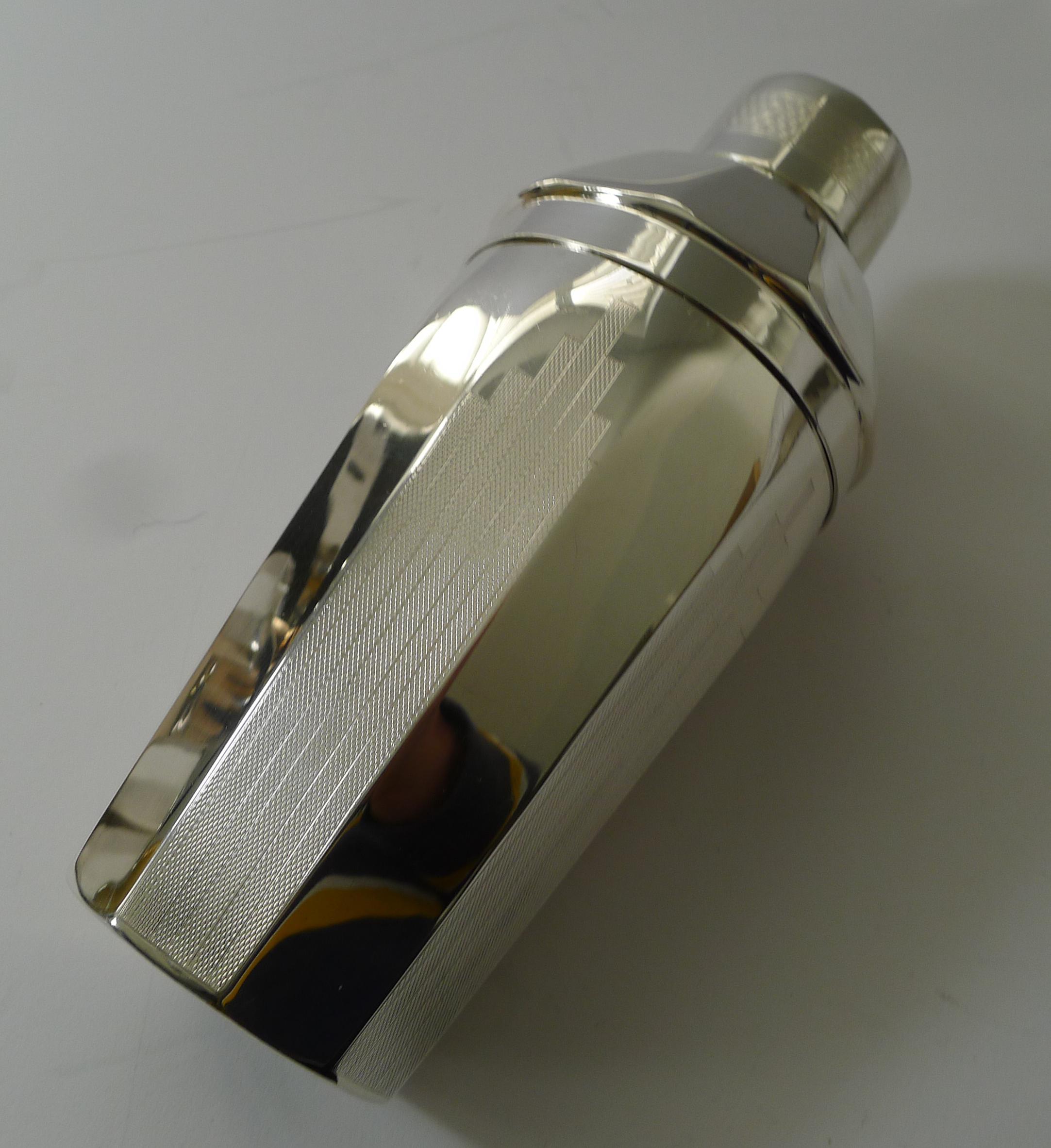 A really unusual vintage silver plated cocktail shaker by the creme de la creme of silver plate manufacturers, Elkington and Co.

The set comprises a very stylish cocktail shaker with a skyscraper engine turned design on alternate facets of the