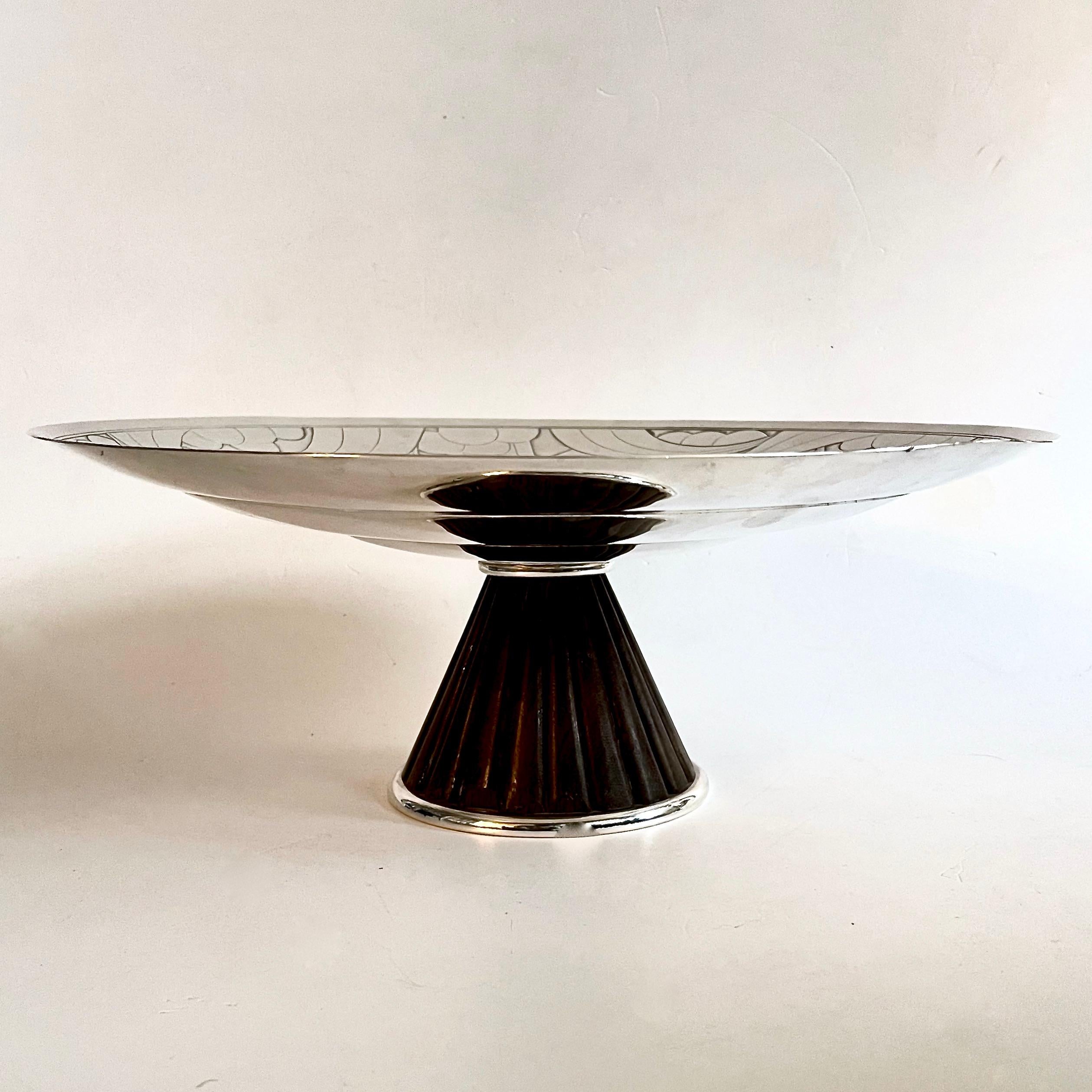 A beautiful large Art Deco silver plated  pedestal bowl. A three tiered concave bowl sits on a cone base of moulded ribbed wood finished with a silver plated surround.  The interior of the bowl is decorated with a geometric abstract pattern of