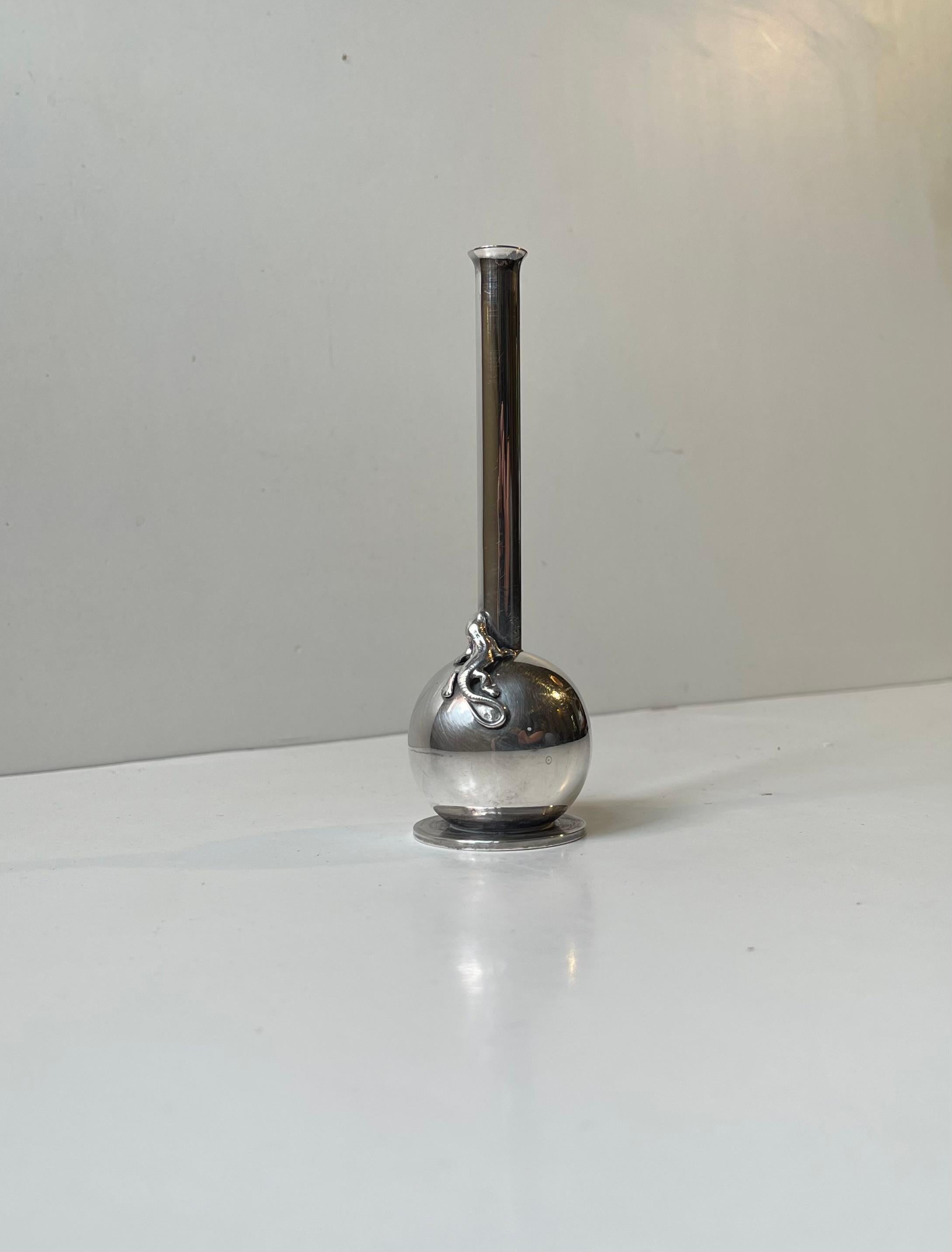 Delicate in appearance this small stylish single-flower vase was made by the Danish Silversmith Hugo Grün during the 1930s. It features a 'guarding' lizard that adorns its circular body and long lean neck. It is executed in high quality silver plate