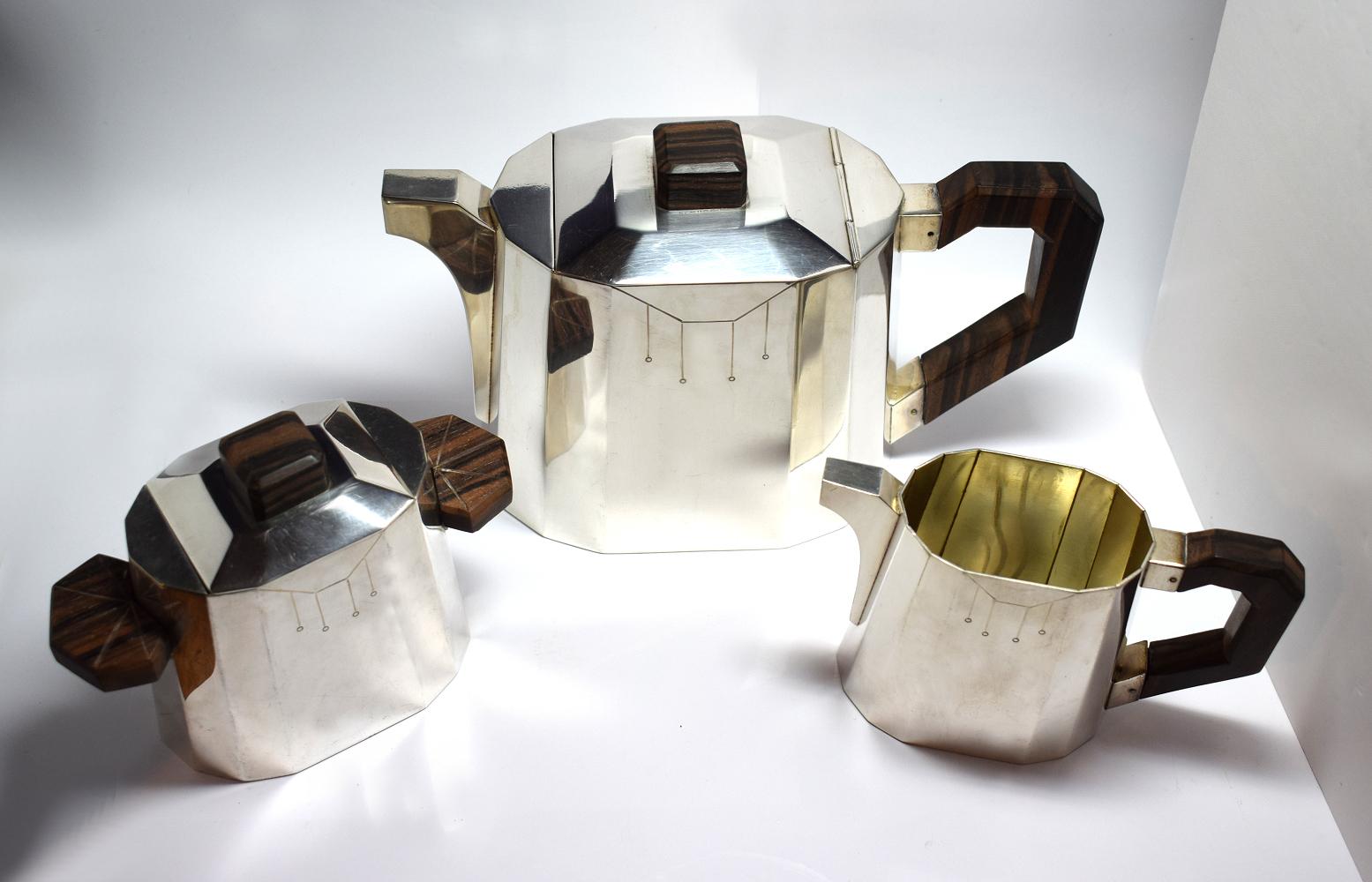 High style modernist silver plated tea set dating to the 1930s and originating from France. Silver plated with Macassar wooden accents, hall marks Goldsmith L.H. Hallmarks with a helmet - White Metal - and other Hallmarks. Comprises milk, sugar, tea