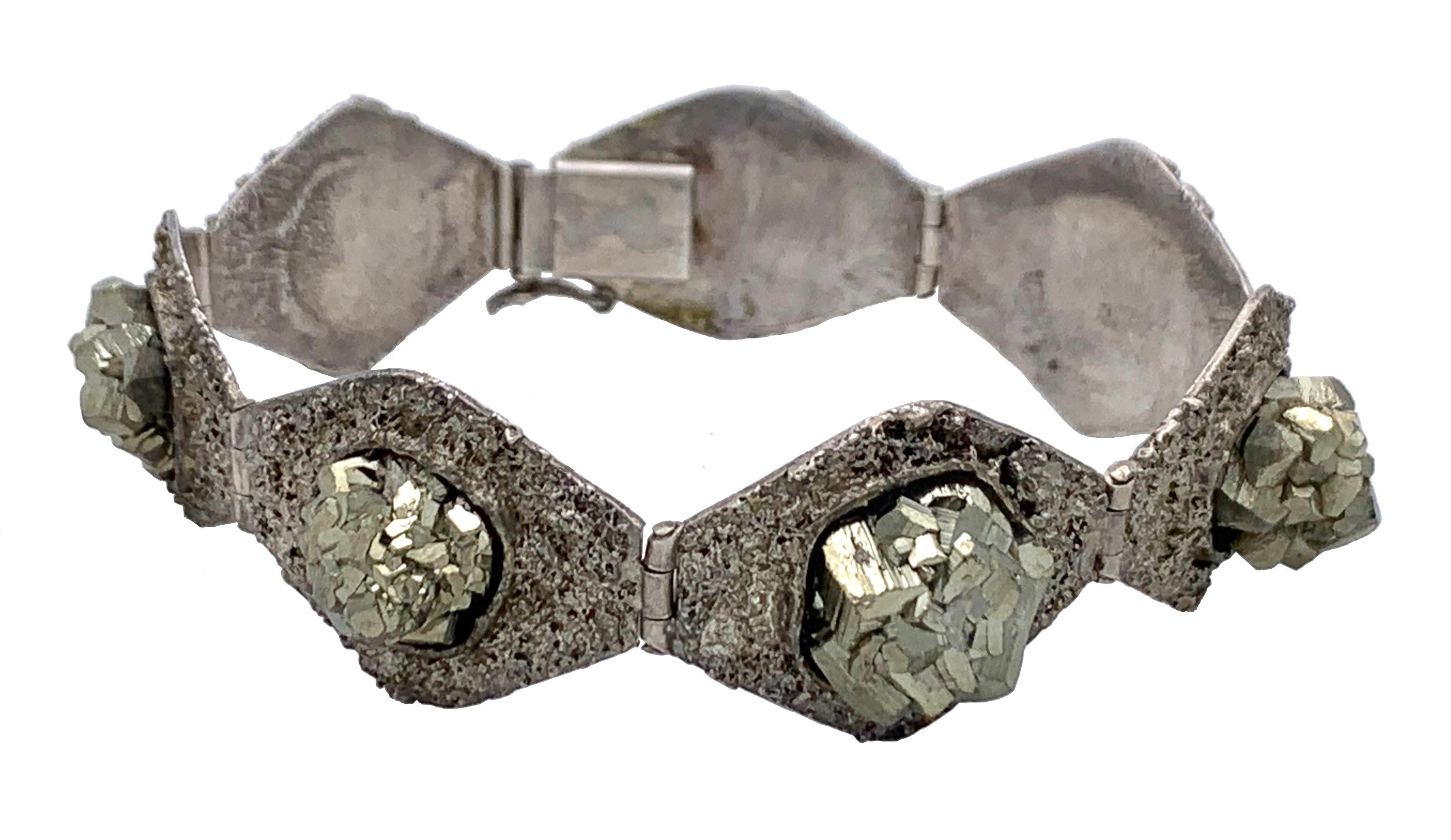 Este inusual y elegante  La pulsera está formada por siete eslabones texturizados en forma de rombo.
Cada eslabón está engastado con un gran cristal cúbico de pirita.
La pulsera está marcada en la lengüeta del cierre con la marca alemana de plata