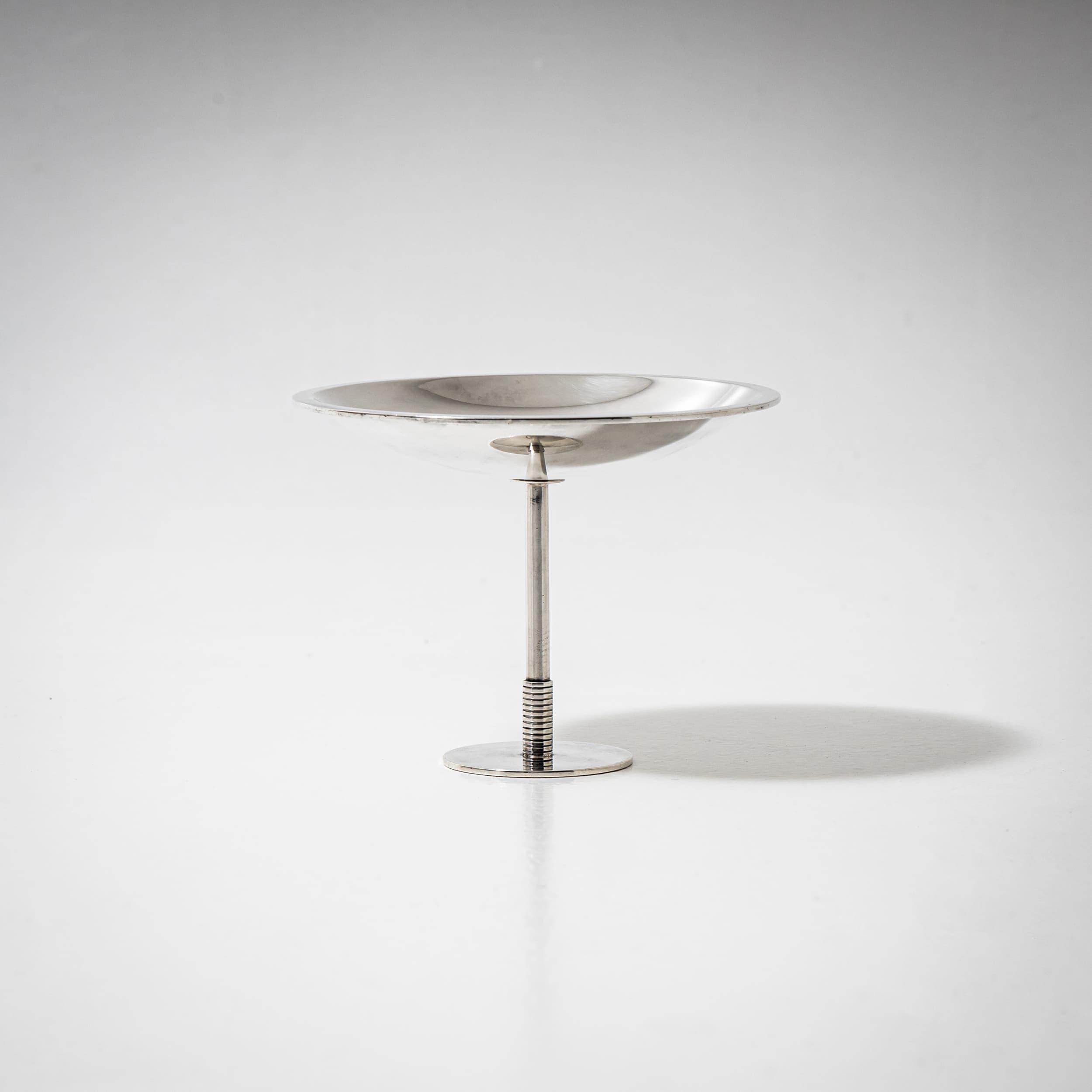 Elegant small tazza with a flat dish, slender stem profiled at the lower third, and a disc-shaped base. Marked on the underside: Sigvard, Denmark, Georg Jensen, Sterling, and Model No. 718. Originally designed in 1932 by Count Sigvard Bernadotte