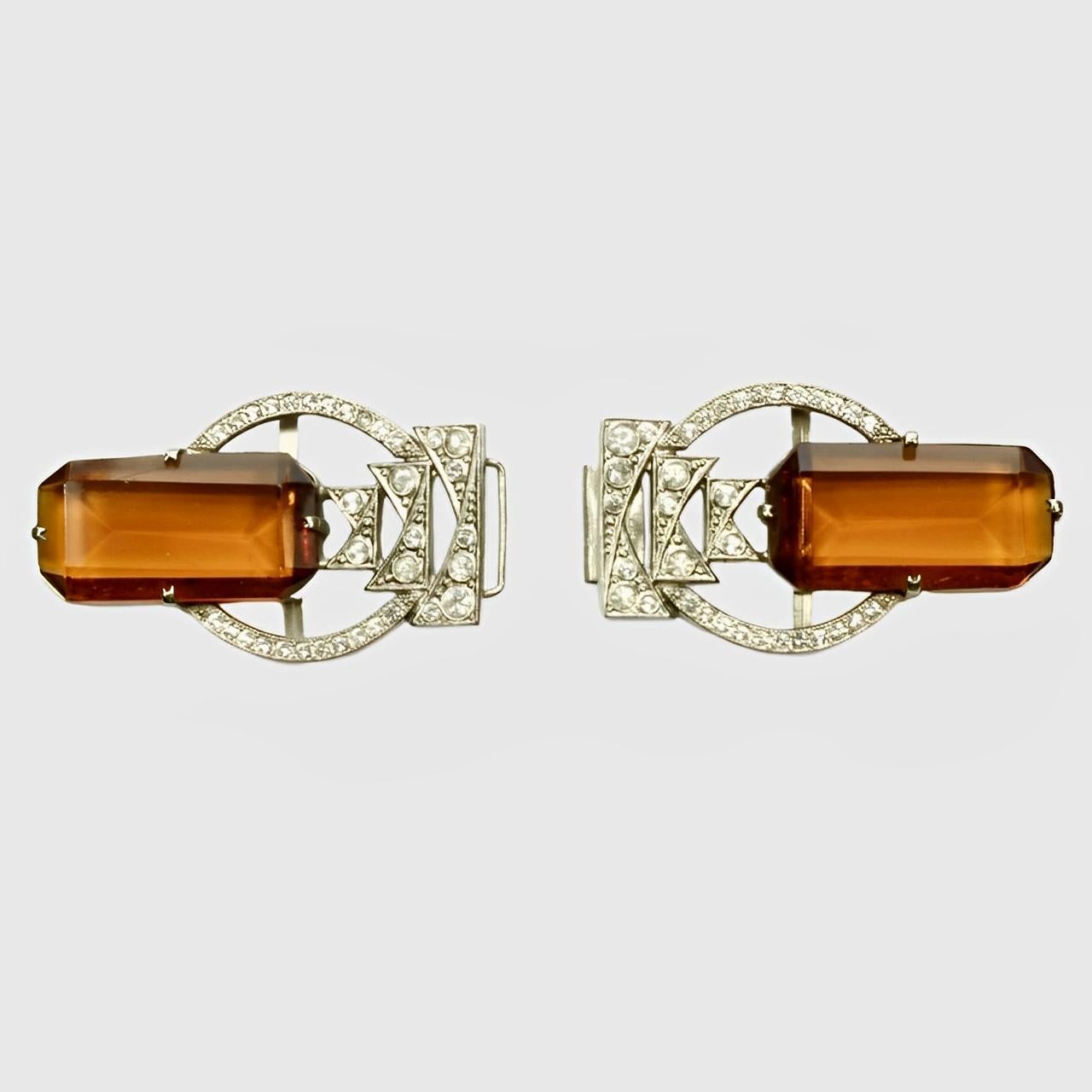 
Beautiful Art Deco silver tone belt buckle featuring amber glass stones, and paste stones with millgrain edging decoration.  

Measuring length 10.1 cm / 3.97 inches by width 3.1 cm / 1.22 inches, it clips together in the middle and would fit a