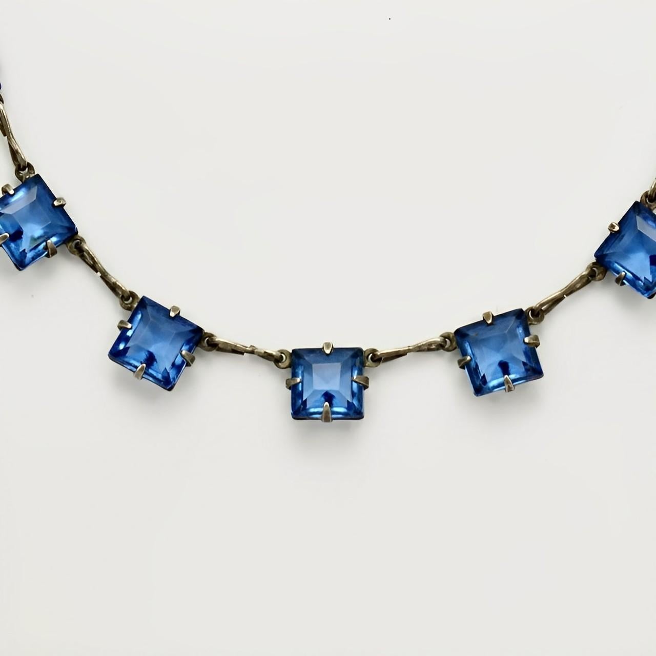 Art Deco silver tone chain necklace featuring beautiful square azure blue crystals in open back settings, with a spring bolt clasp. The faceted crystals are raised at the front and pointed at the back, for maximum sparkle. The chain links are