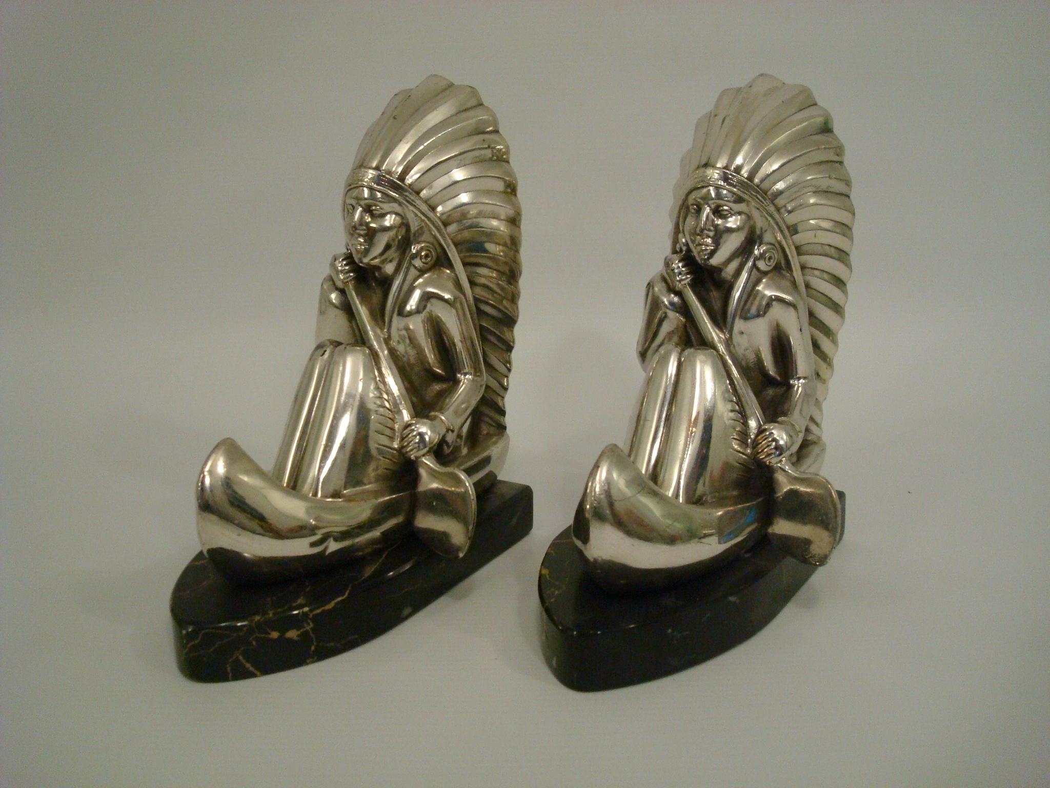 Art Deco silvered metal natives rowing bookends.
In the style of Noel Coulon, French artist.
A pair of art deco silvered metal bookends, mounted over black and gold italian marble bases.
 