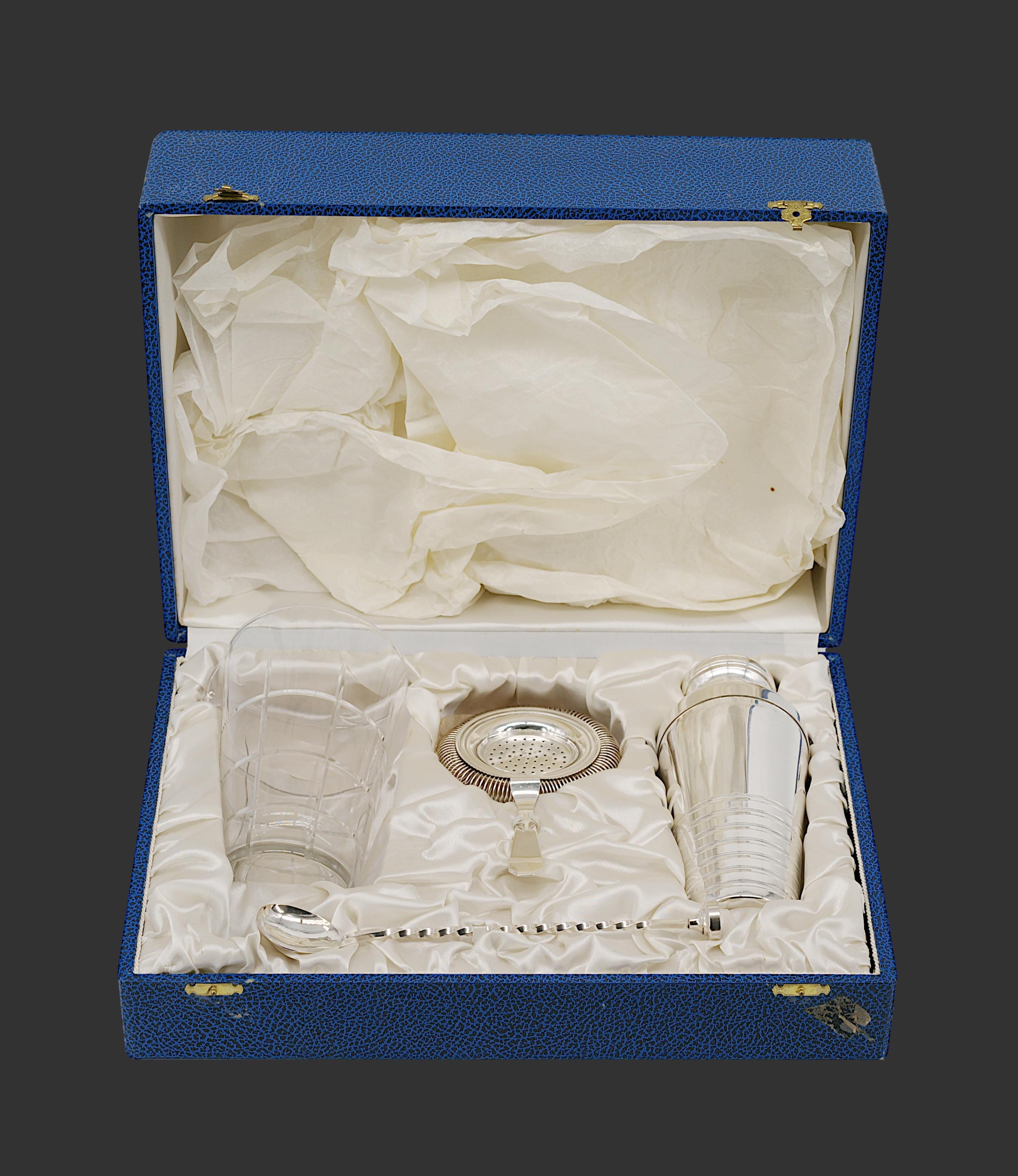 Caja francesa Art Decó del juego de cocteleras Cobbler, Francia, ca.1920. Chapa de plata y cristal. Caja, coctelera, vaso mezclador, cuchara mezcladora y colador de hielo. Caja - Alto: 13,8 cm, Ancho: 38 cm, Fondo: 28 cm. Agitador - Altura: 19,3 cm