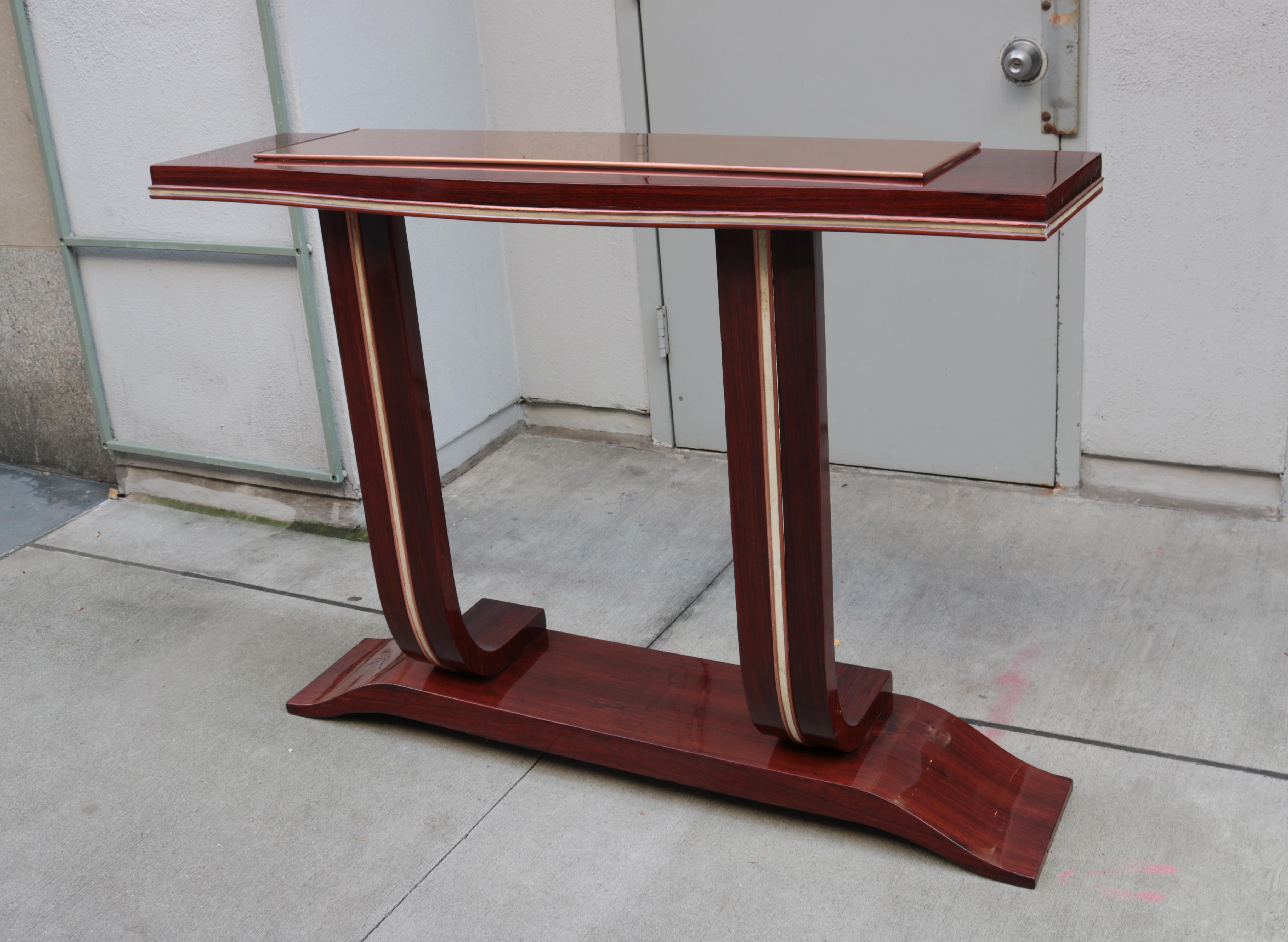 Una console Art Deco. 
Mogano con intarsi in pergamena, dettagli in rame e piano a specchio.