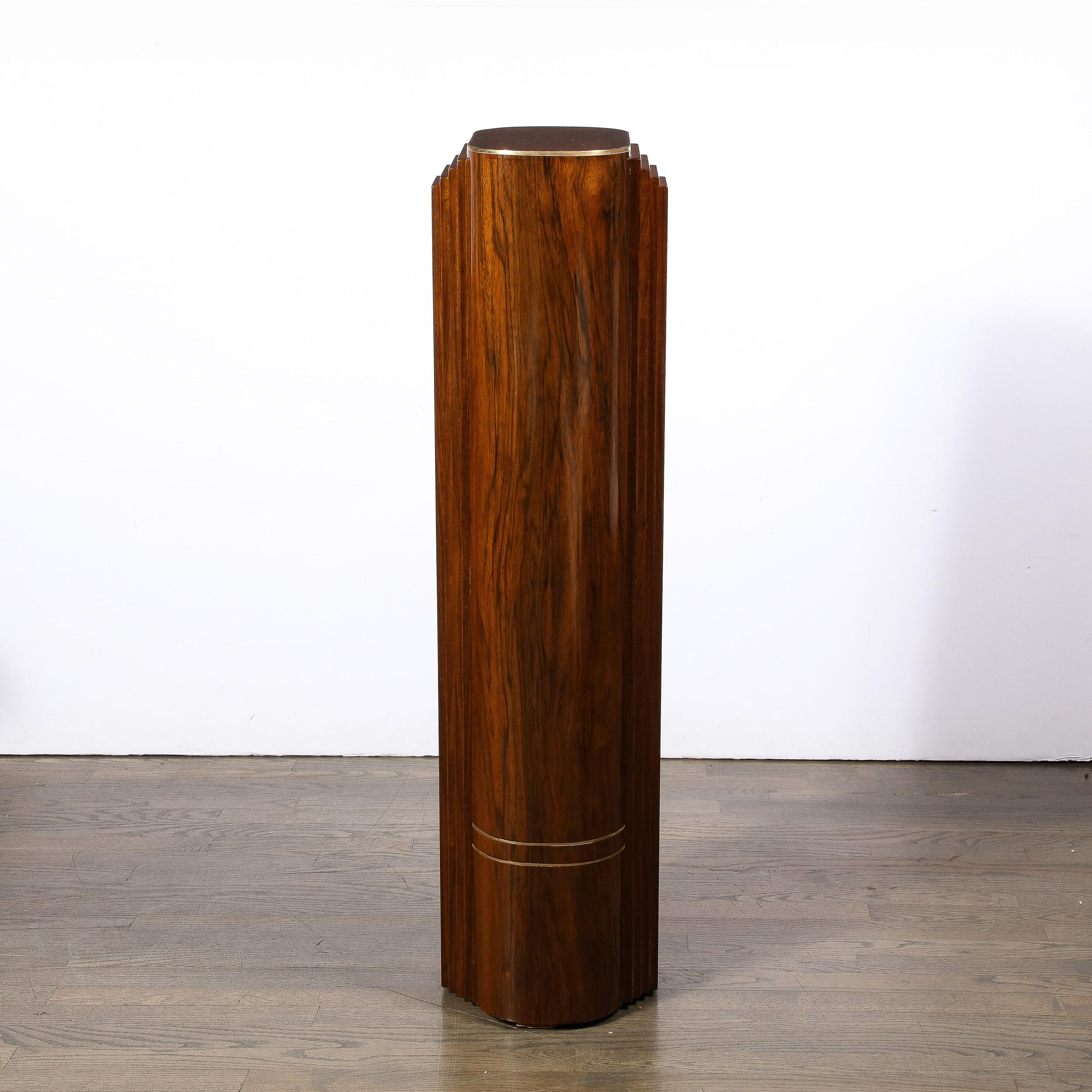 This remarkable Art Deco Skyscraper Style Hand-rubbed Book-matched Walnut Pedestal w/ Brass Inlays originates from France circa 1935. Featuring a construction in solid walnut with a beautiful hand-rubbed finish, one can observe subtle strips of