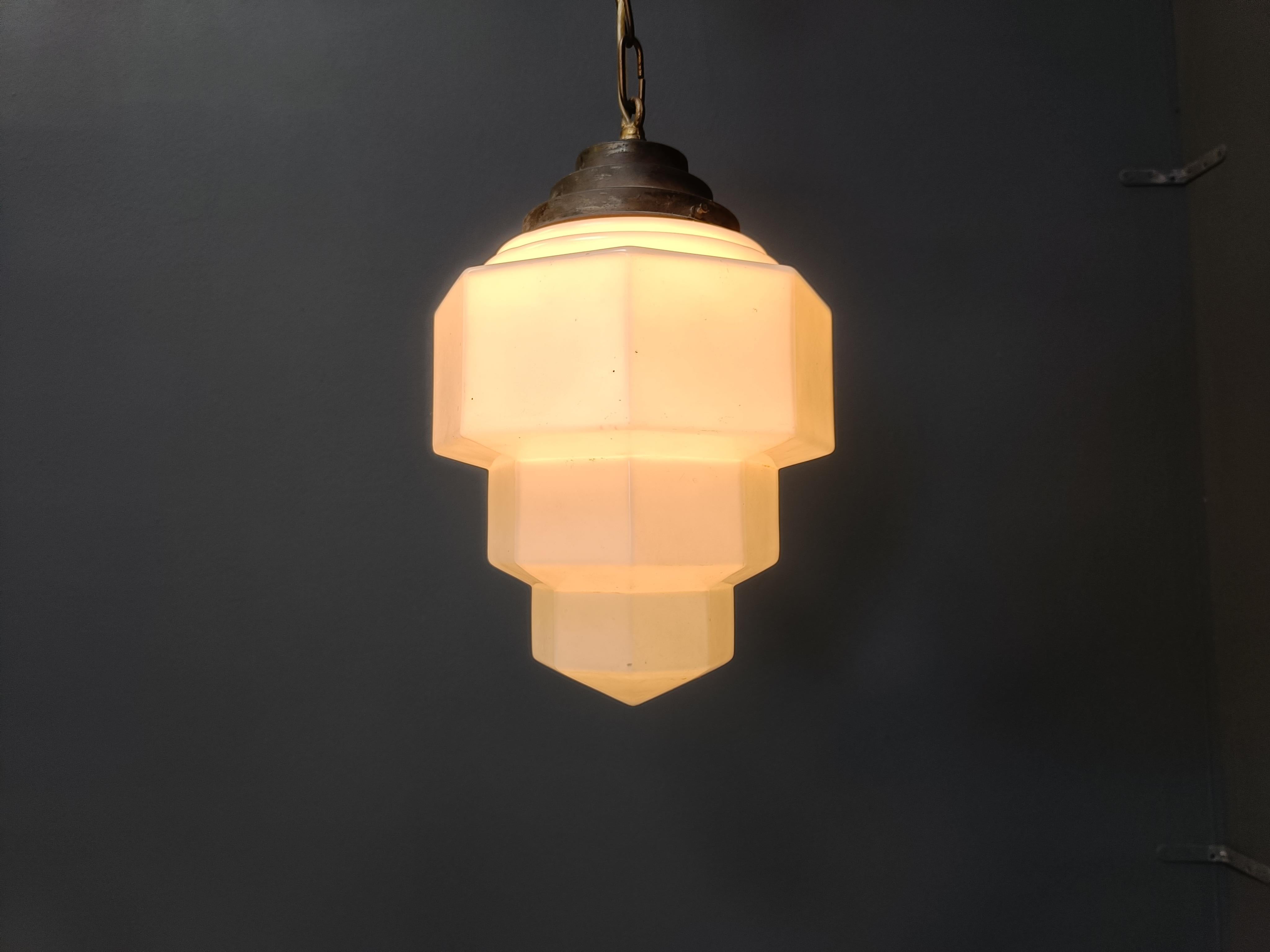 Antique art deco hallway pendant light.

This skyscraper design lamp is very typical for the art deco era and was widely used to be hung in hallways, offices or larger public places.

The lamp has the original stepped shade holder and ceiling
