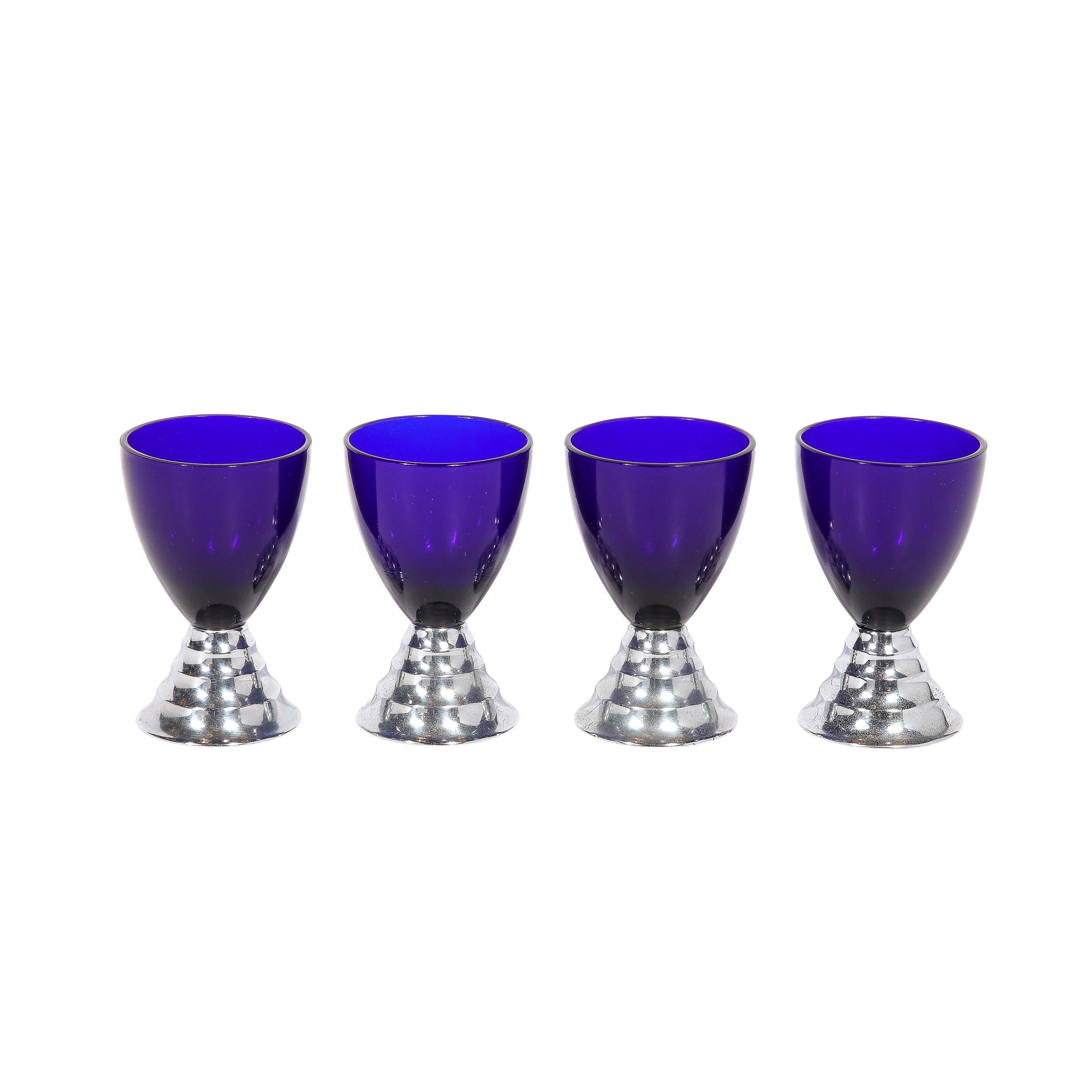 This stunning set of twelve Art Deco cocktail glasses were realized in the United States circa 1930 by the renowned maker Chase. They feature hourglass forms consisting of conical chrome skyscraper style bases featuring circular rings that diminish