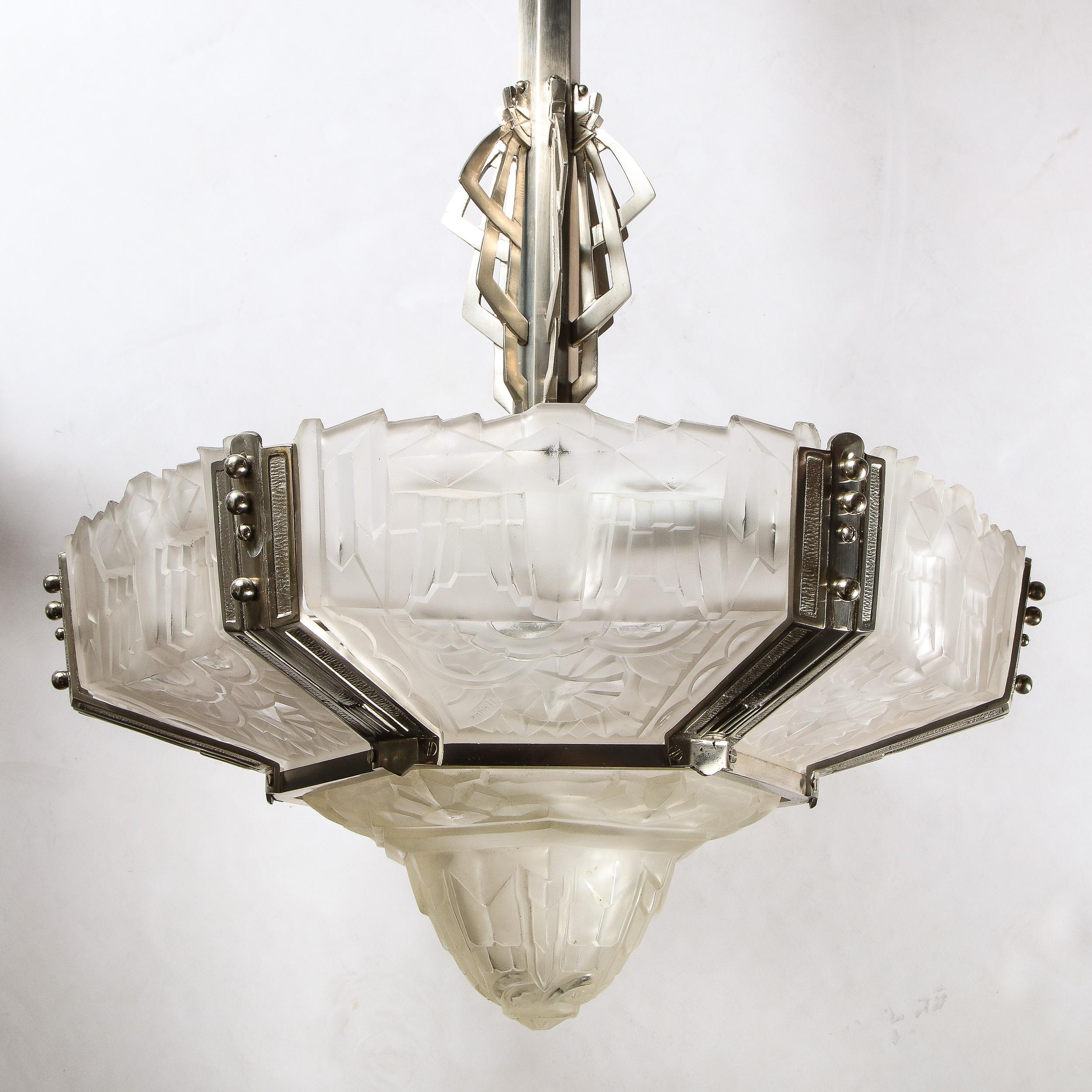 This rare and special Art Deco chandelier features six frosted relief glass panels with a center coupe all in a highly stylized Cubist geometric and floral motif ,all signed Hugue .The glass panels are fitted with a nickled bronze frame in a