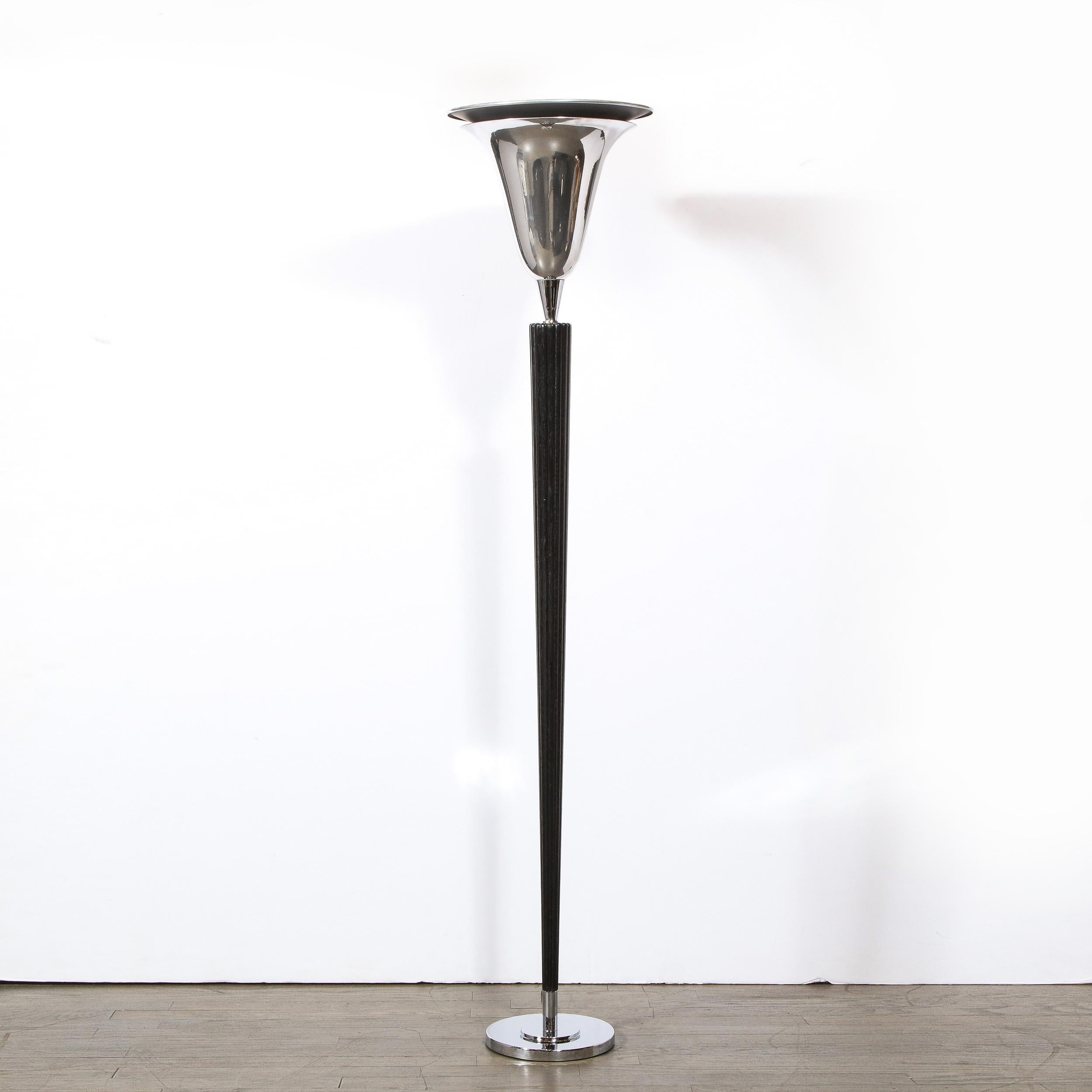 This elegant Art Deco torchiere was realized in the United States, circa 1940. It features a skyscraper style circular tiered base; a channeled ebonized walnut body that tapers to its nadir; and a two-tiered billowing shade in lustrous chrome. With