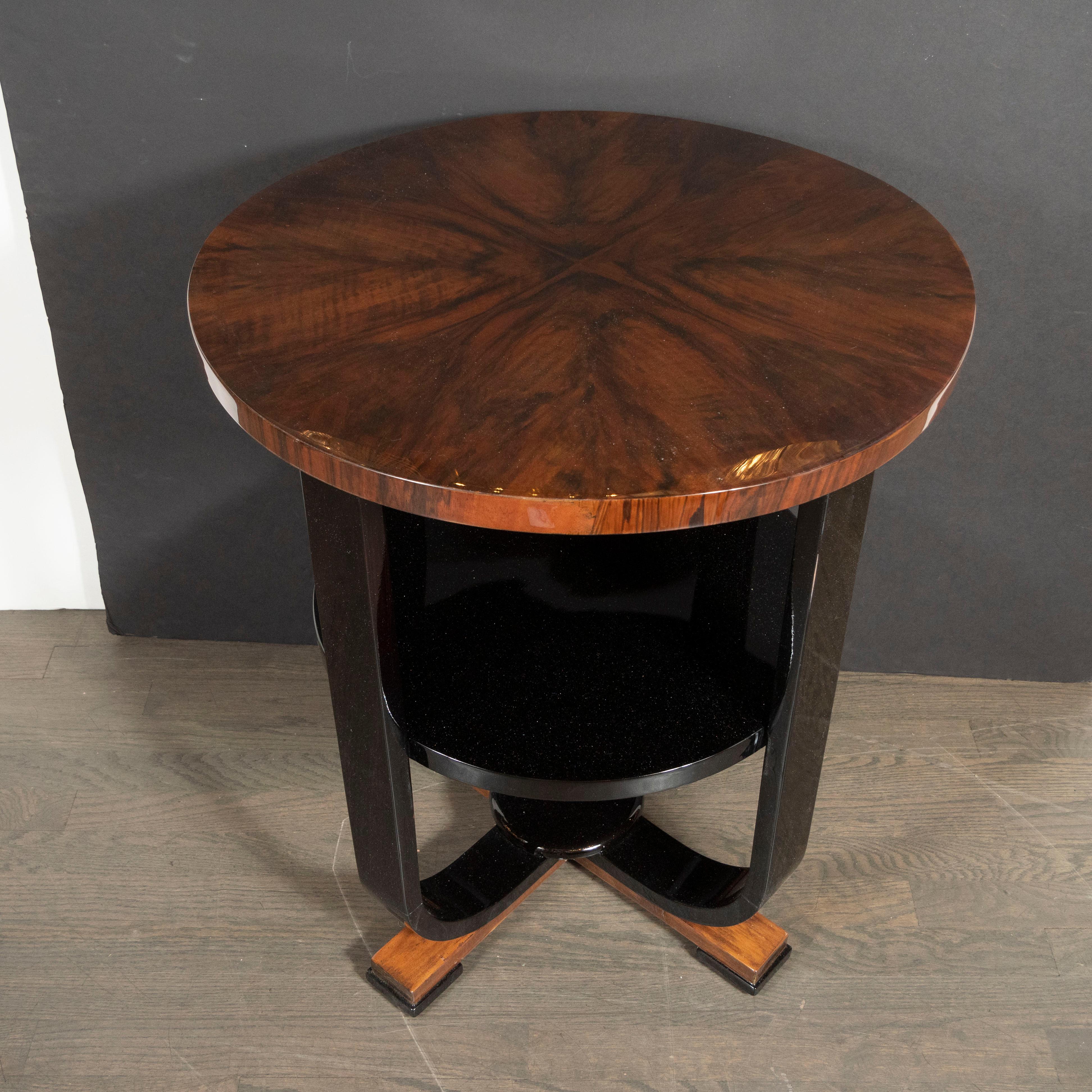 This stunning side/ gueridon table was realized in the United States, circa 1930. It features two tiers- the upper in a bookmatched and burled walnut, and the lower in black lacquer- with four skyscraper style feet in alternating lacquer and walnut.