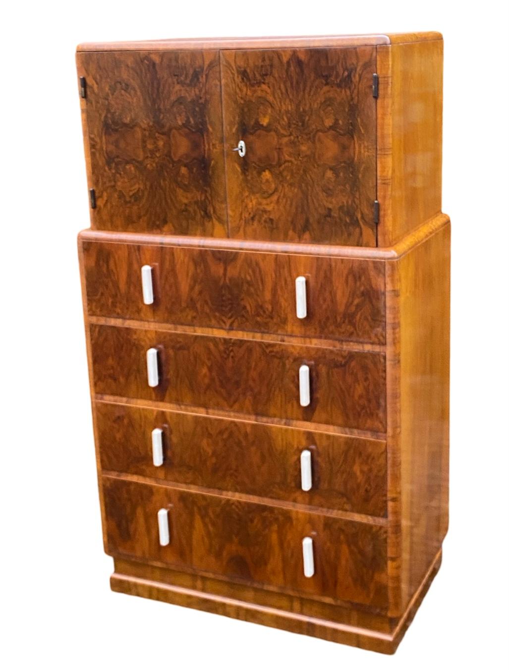Magnifique porte-tout en noyer figuré, datant de 1930, de style Art déco. Les 4 tiroirs profonds et gradués fonctionnent en douceur et sont dotés de belles poignées en phénolique blanc avec des supports chromés assortis à l'écusson de clé en