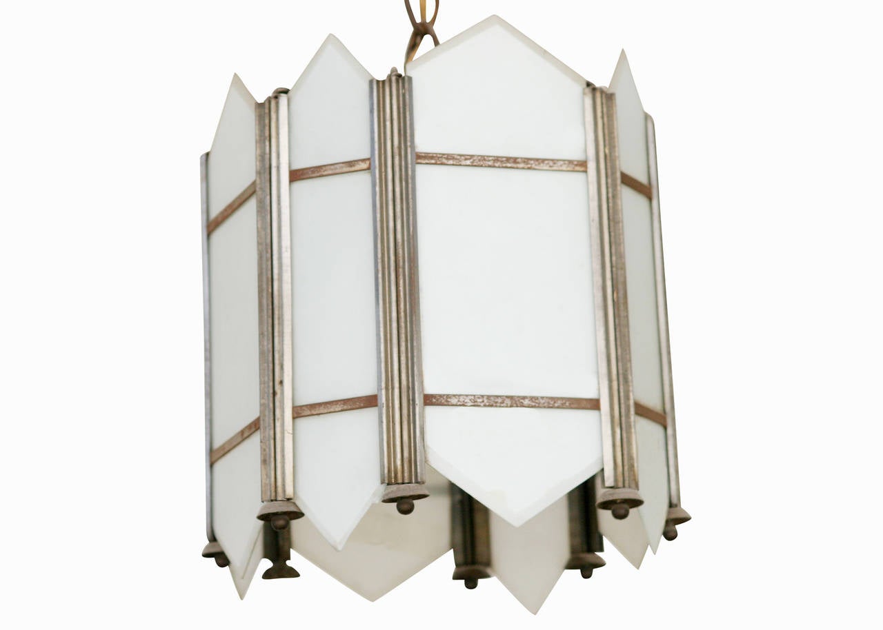 Made circa 1920, this Art Deco ceiling pendant has an intricate geometric design with slat white flash opal glass inserts.