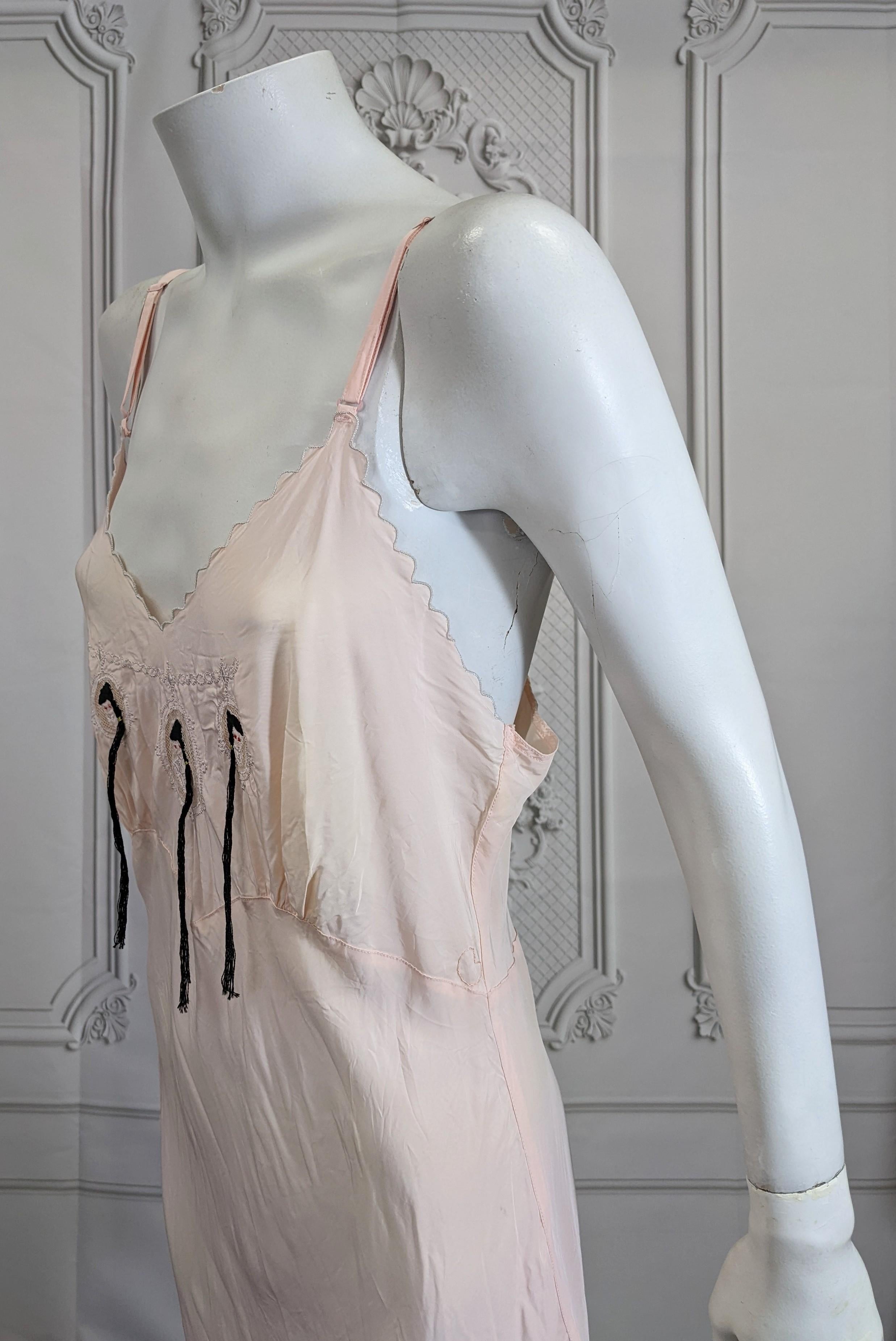 Art Deco Slip Dress, Upcycled by Studio VL. Period 1930's rayon pink slip dress with cameo embroidery of 3 maidens. Hand embroidered hair and ponytails have been added to the 3 maidens in black cotton with red pupils for a twisted accent. 
Small