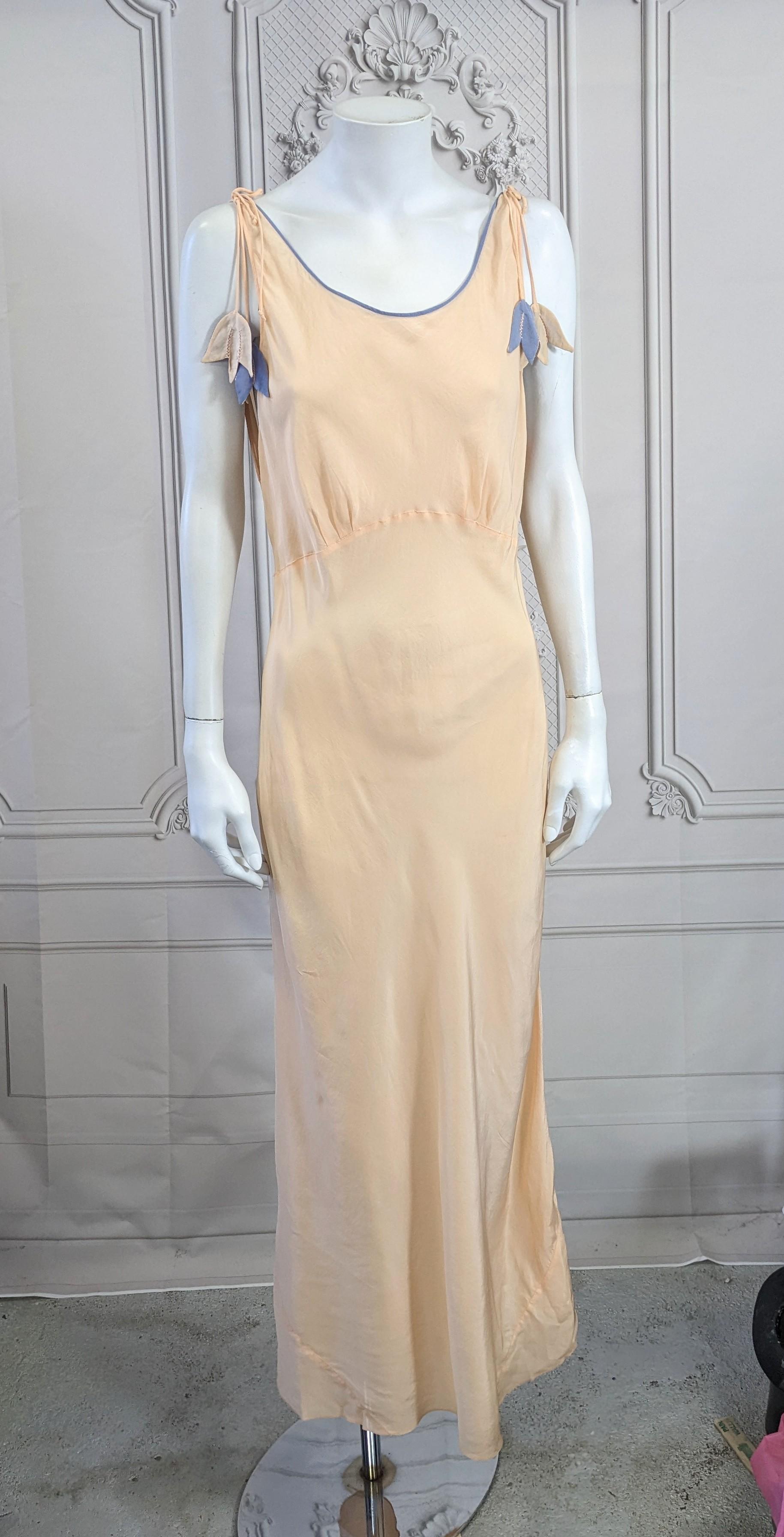 Unusual Silk Art Deco Slip Dress with Bell Flower motifs. Peachy pink and lavender silk are mixed in this charming bias slip dress with a pair of reversible silk bell flower motifs hanging from each shoulder. Deep cut armholes.  Small size 2-4,