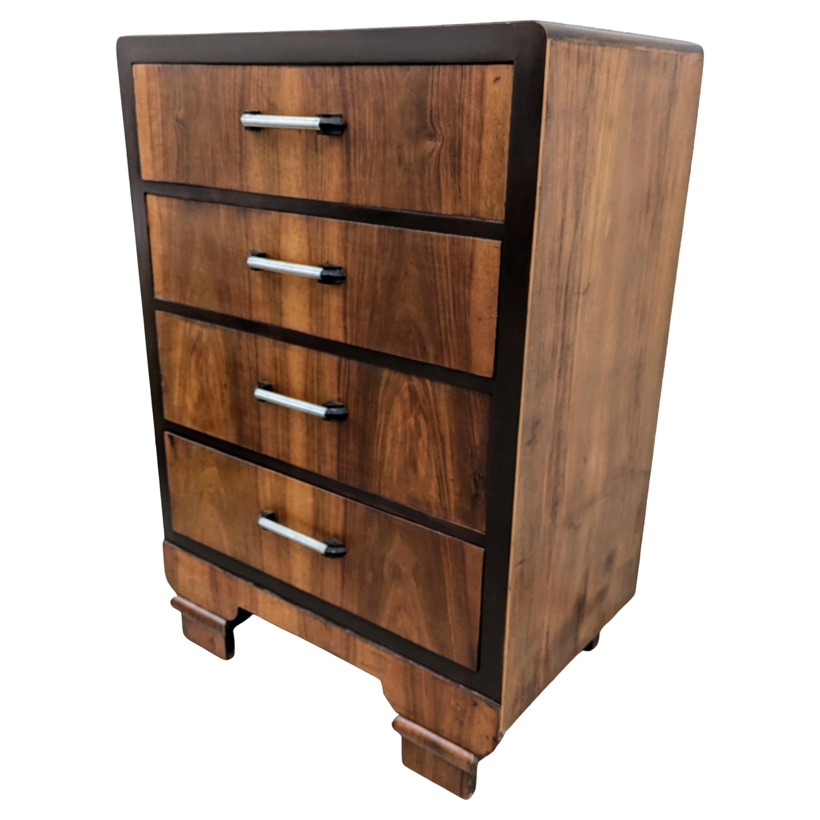 A very stylish Art Deco walnut chest of four drawers originating from England and dating to the 1930's is offered for your consideration. It has very attractive walnut veneers with original Art Deco handles in black bakelite & chrome. Book matched