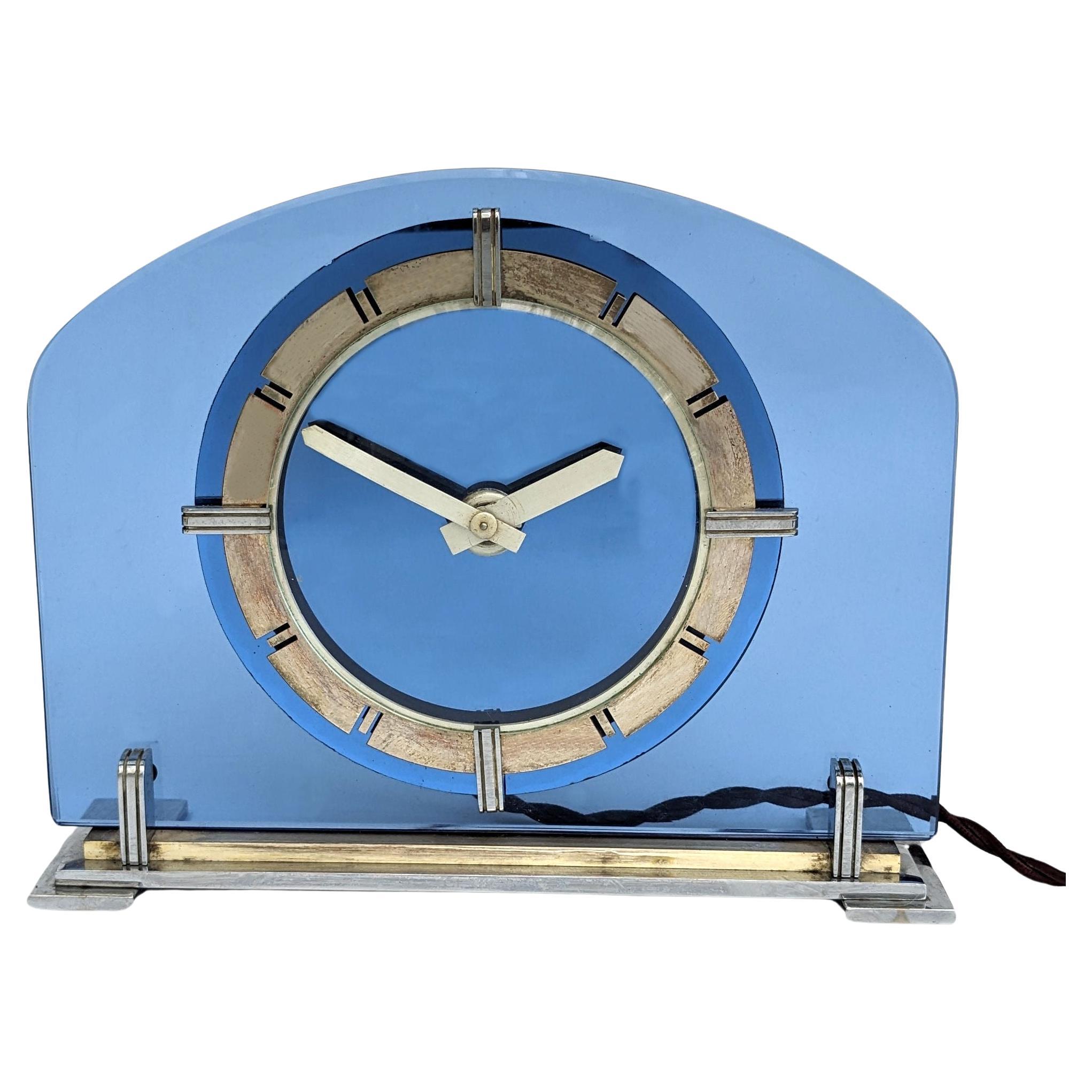 Large and rare and stunning Art Deco blue glass, brass Electric Mantle clock. This clock is an absolute delight. This glamourous clock features a brass bezel with fretted out numerals and a mirrored blue glass dial. The clock as with all our clocks