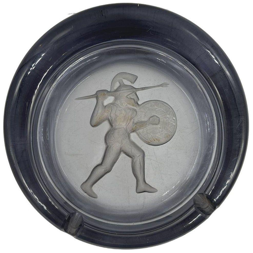 Art Deco era Smoked Blue Art Glass ashtray with a raised relief of a Spartan Warrior with spare in hand and hand-etched details. The thickness of the glass enhances the richness of the deep blue color, creating depth and an almost jewel-like quality