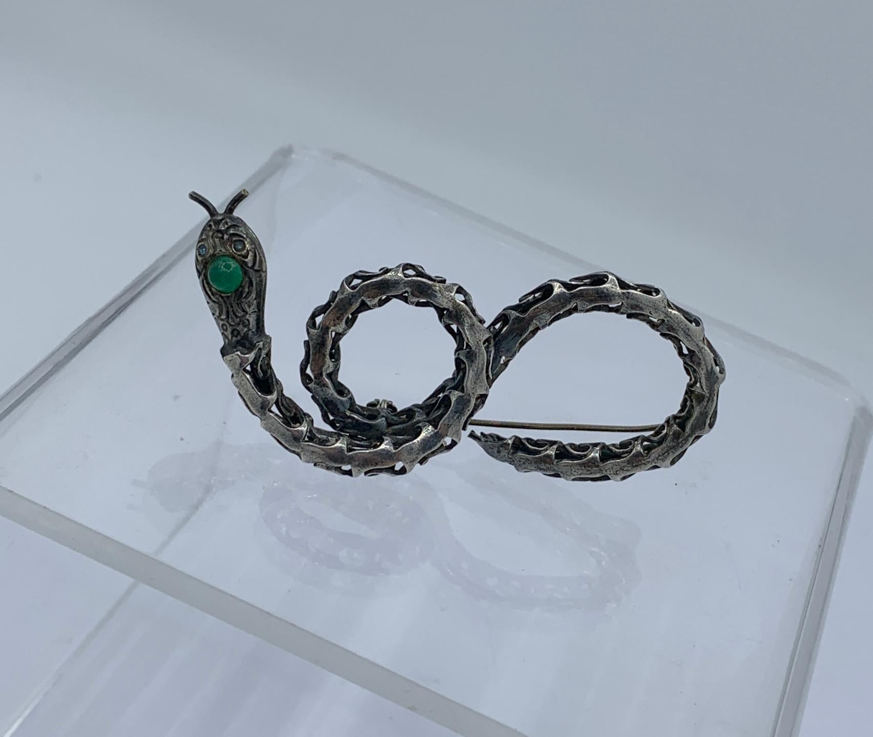 THIS IS A STUNNING ANTIQUE SNAKE BROOCH IN THE FORM OF A CURLING SNAKE IN FINE SILVER IN AN OPEN WORK DESIGN.  THE HEAD AND EYES OF THE SNAKE ARE SET WITH GREEN CHRYSOPHRASE GEMS.
The snake brooch has wonderful design and Art Deco - Mid-Century