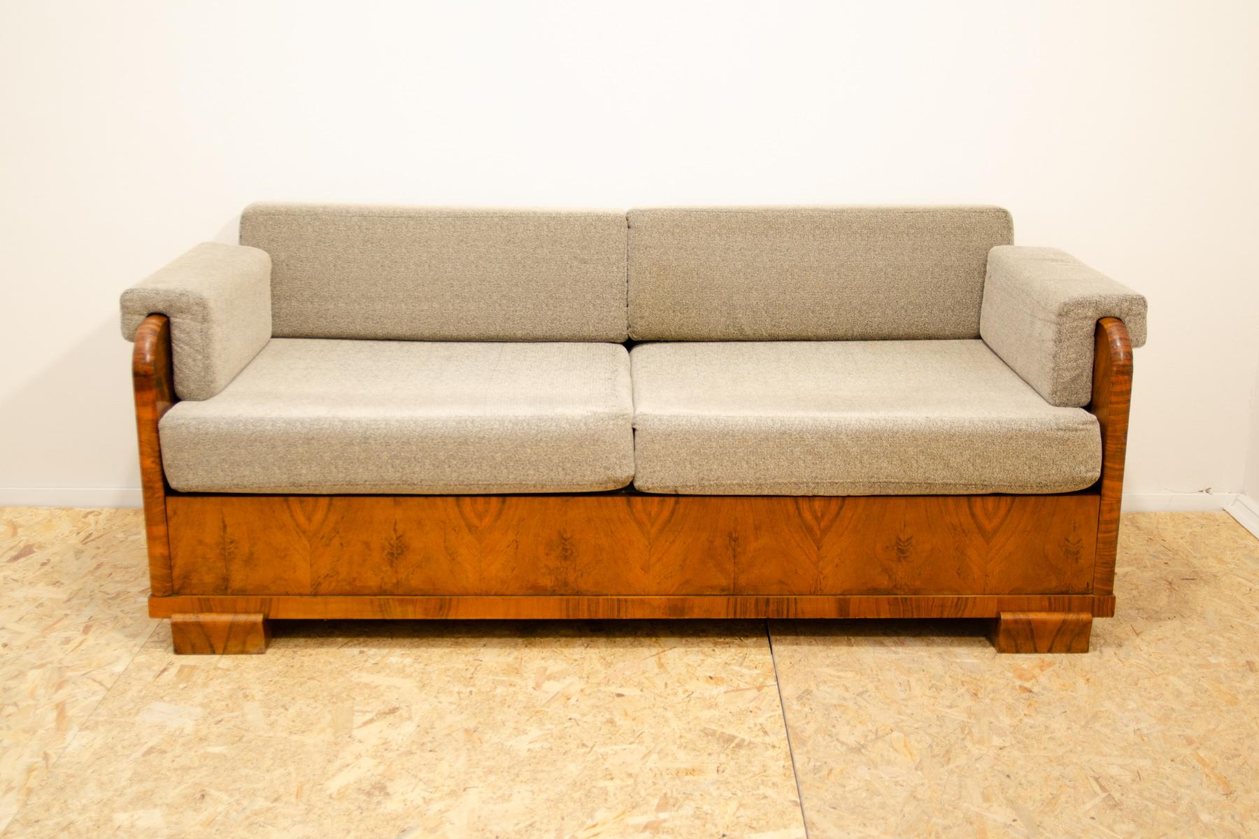 ART DECO couch, made in the 1930s in the former Czechoslovakia. It is made of walnut wood, has upholstered armrests and storage space for bedding. The upholstery has been cleaned, the wood is basically in very good condition, only in one corner
