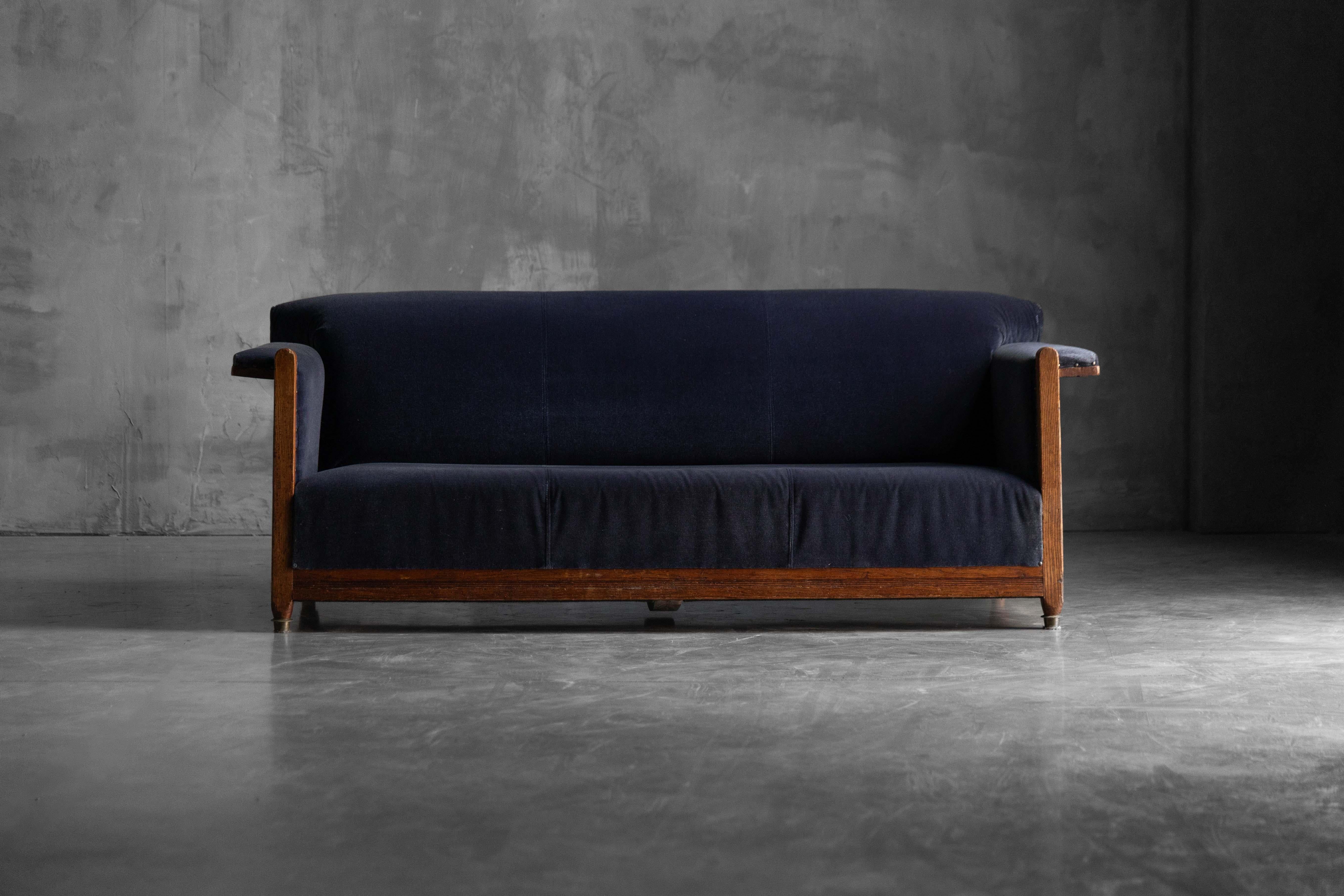 This Dutch Art Deco sofa from the 1920s features a minimalist silhouette with bold geometric lines, characteristic of the Hague School. Upholstered in deep navy blue mohair velvet, the sofa is gently softened by a subtly aged patina. The solid oak