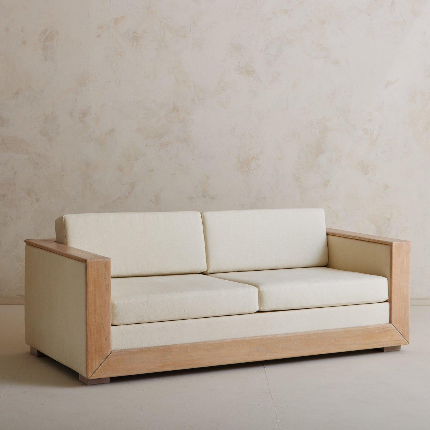 Ein Sofa im Art-Déco-Stil, neu gepolstert mit einem cremefarbenen Strukturstoff. Dieses Sofa hat eine Verkleidung aus gebrannter Eiche und steht auf vier Holzfüßen. Wir lieben die kantigen Linien und das elegante Profil dieses Klassikers. Stammt aus