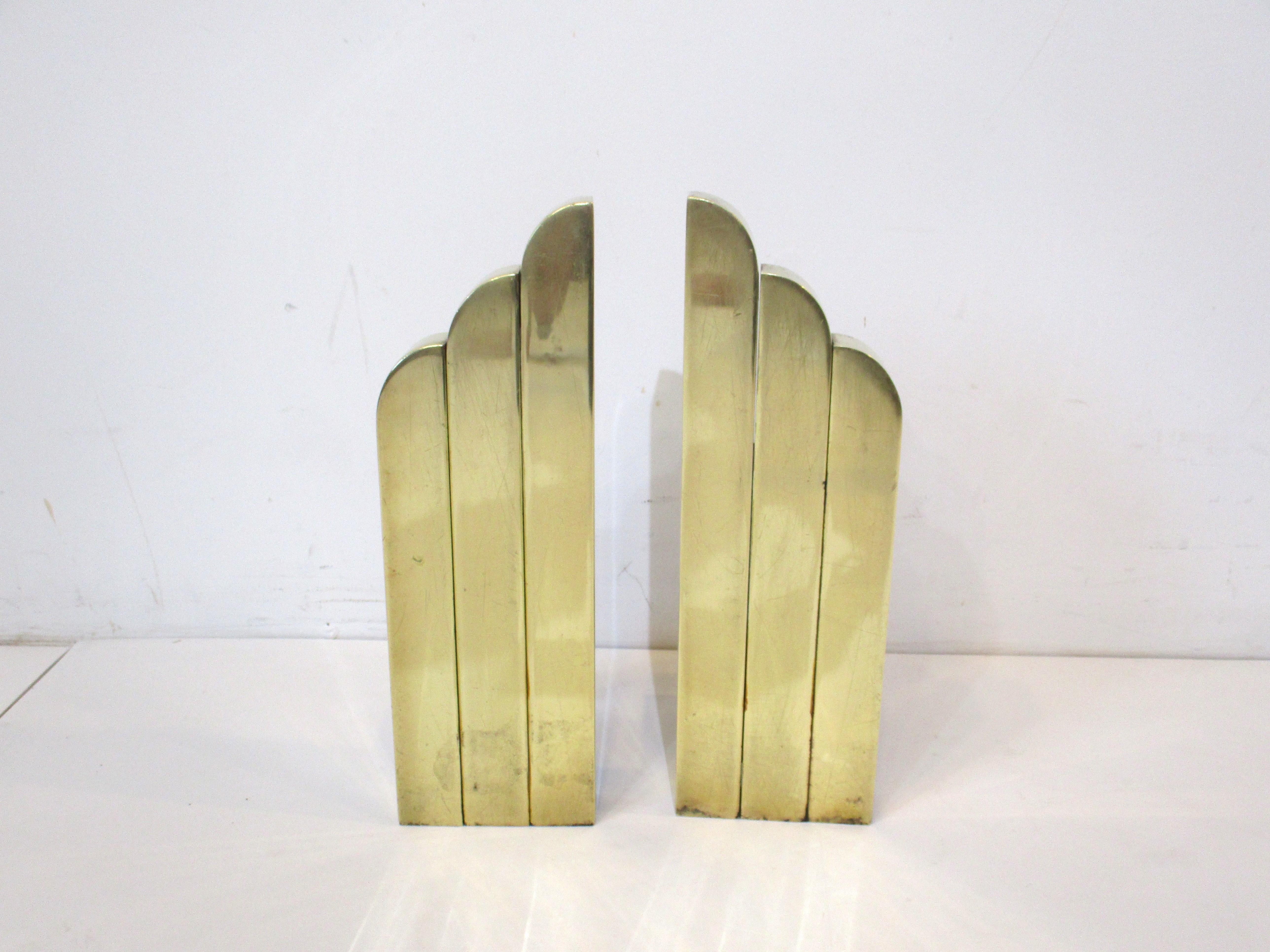 A pair of very well crafted vintage Art Deco streamline skyscraper fireplace andirons in solid brass with iron back legs. Having a scalloped top with waterfall design giving them a sophisticated and rich look , each piece has numbers and letters