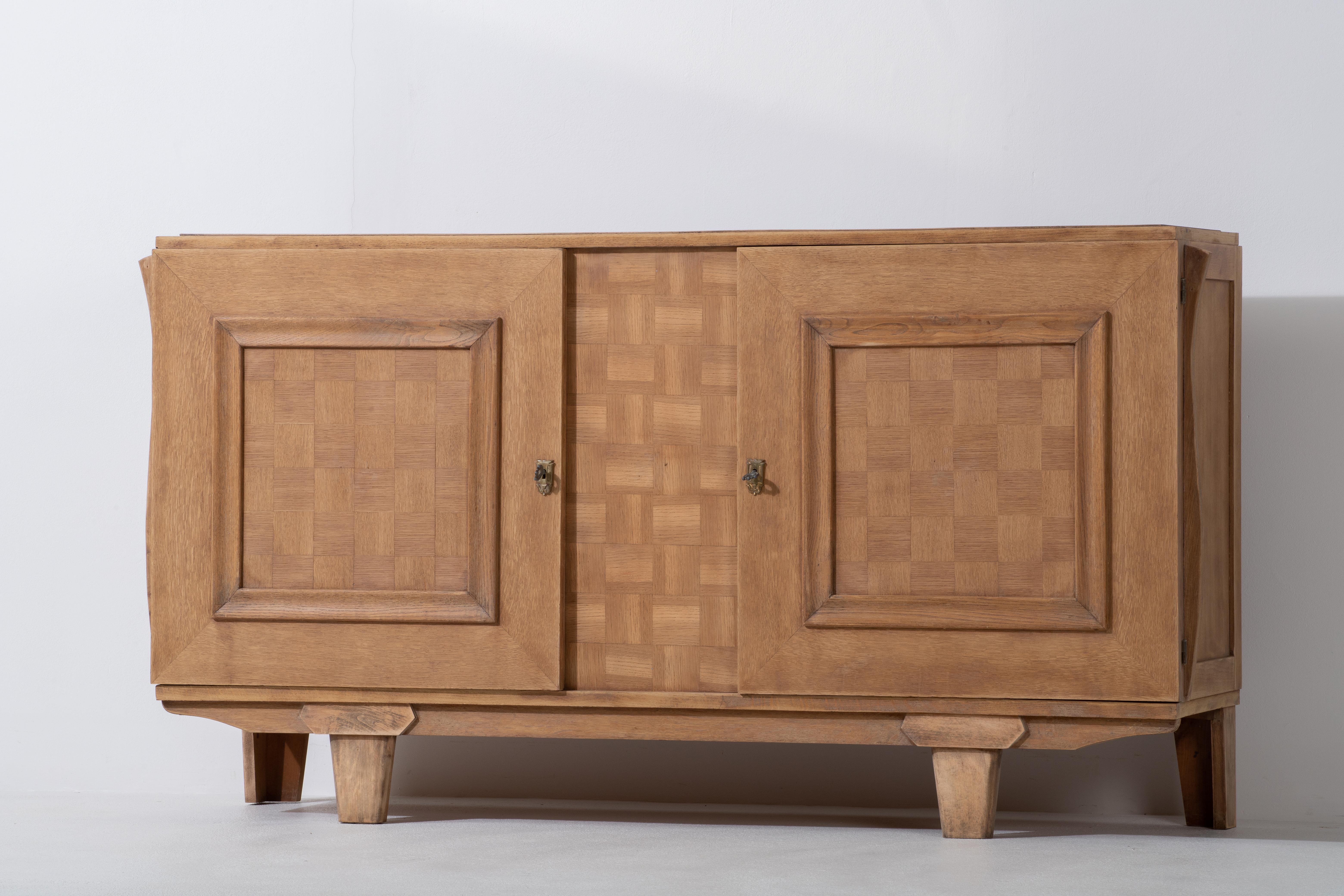 Very elegant credenza in solid oak, France, 1940s.
Large Art Deco Brutalist sideboard. 
The credenza consists of two storage facilities and a central drawer column and covered with very detailed designed doors. 
Very elegant.
The refined wooden