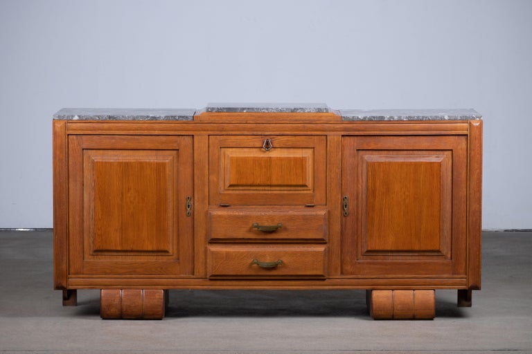 Large Art Deco sideboard, France, 1940.
The credenza consists of three storage facilities with a handcarved central door.
The refined wooden structures on the doors create a striking combination with the otherwise sturdy and solid cabinet.

The