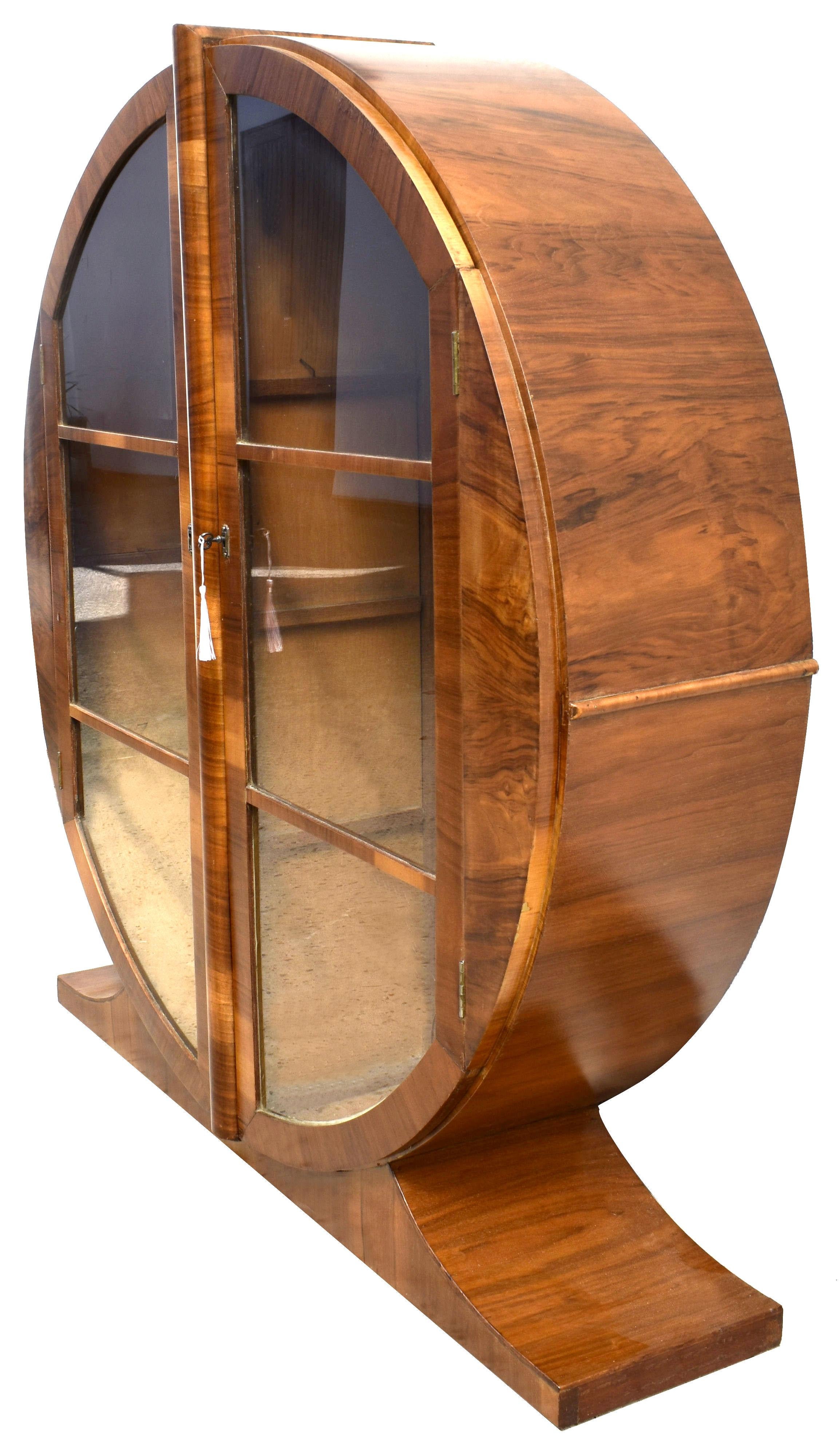 Offered for your consideration is this superbly stylish and totally original 1930s English Art Deco round display cabinet. Figured walnut veneer in a warm mid-tone coloring with a distinctive light and dark alternation running throughout and
