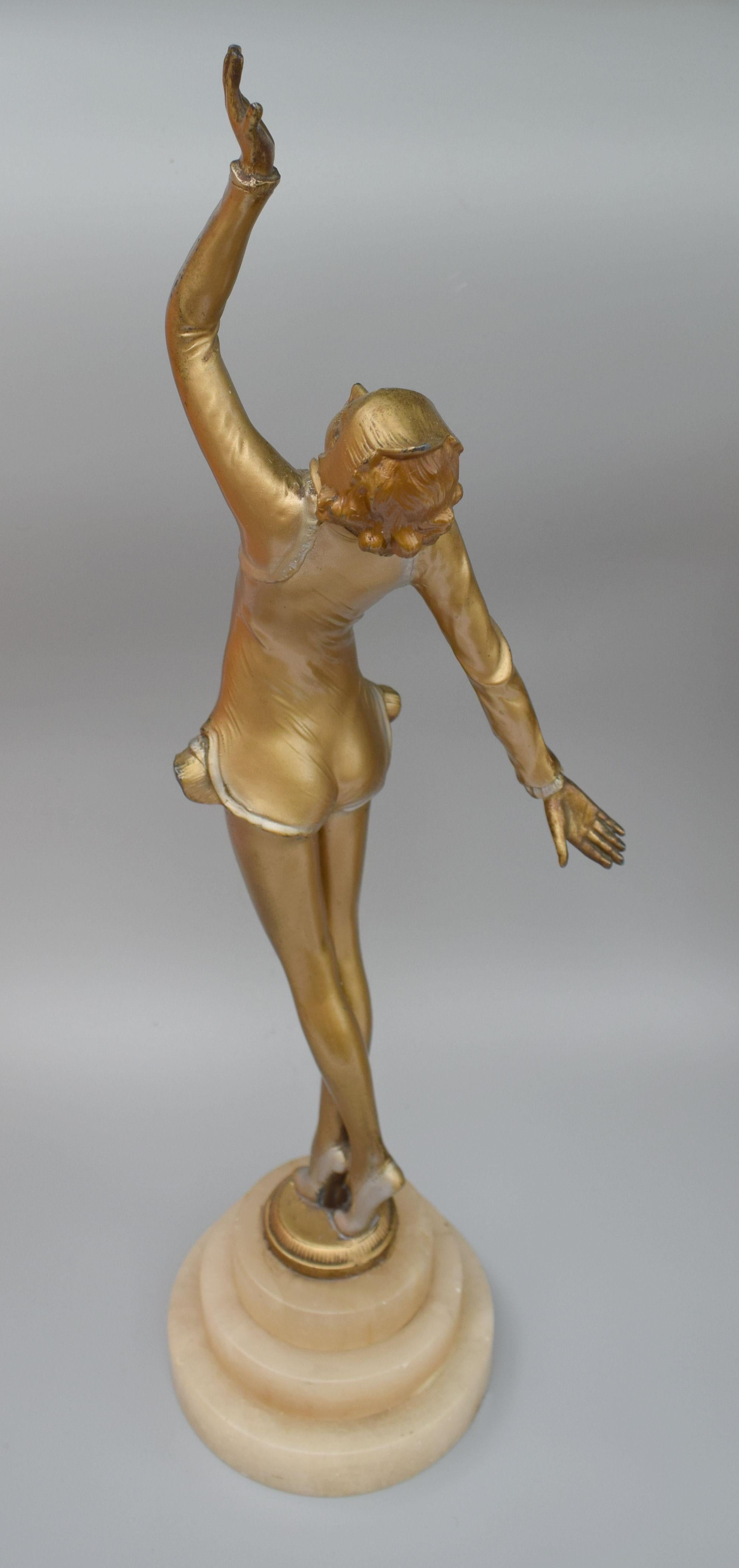 Une très élégante et originale figurine Art Déco des années 1930 d'une dame en Spelter peint à froid. Elle repose sur un socle en albâtre, circulaire et étagé. Portant la mode de l'époque (années 1930) avec des bas de corps et des chaussures à