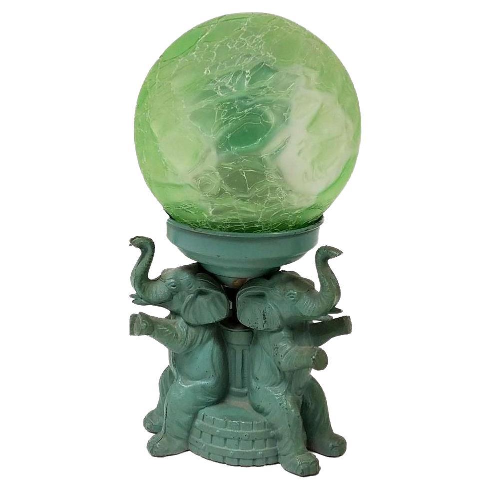 Original Art Deco spelter metal elephant lamp with crackle shade signed A.P.T. NY. The lamp features 3 enameled green elephants sitting on a column holding up a green glass crackle shade.

1920, United States