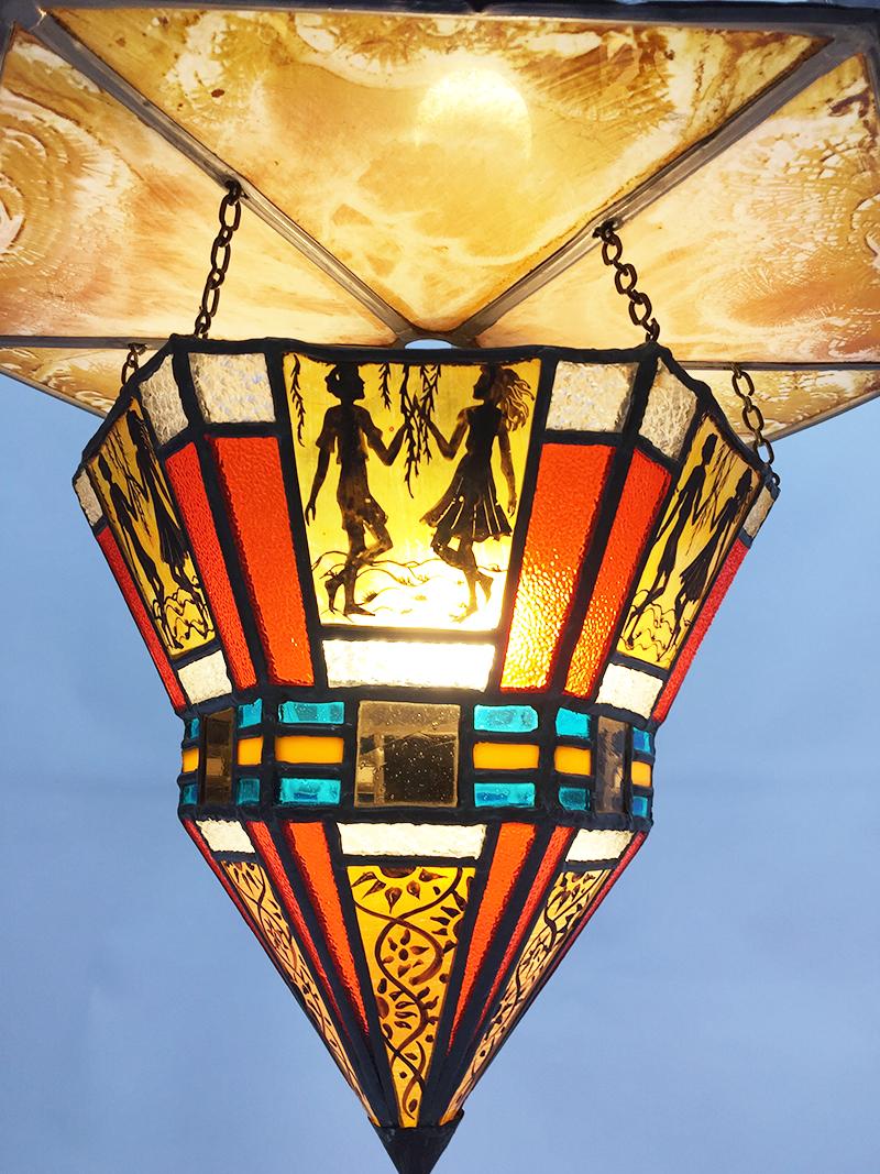 Art Deco stained glass ceiling lamp

A white plate in the shape of a ring connected to the ceiling. The stained glass lampshade is connected with chains to the hexagonal stained glass plate. The lamp is made of stained glass in the colors blue, red,