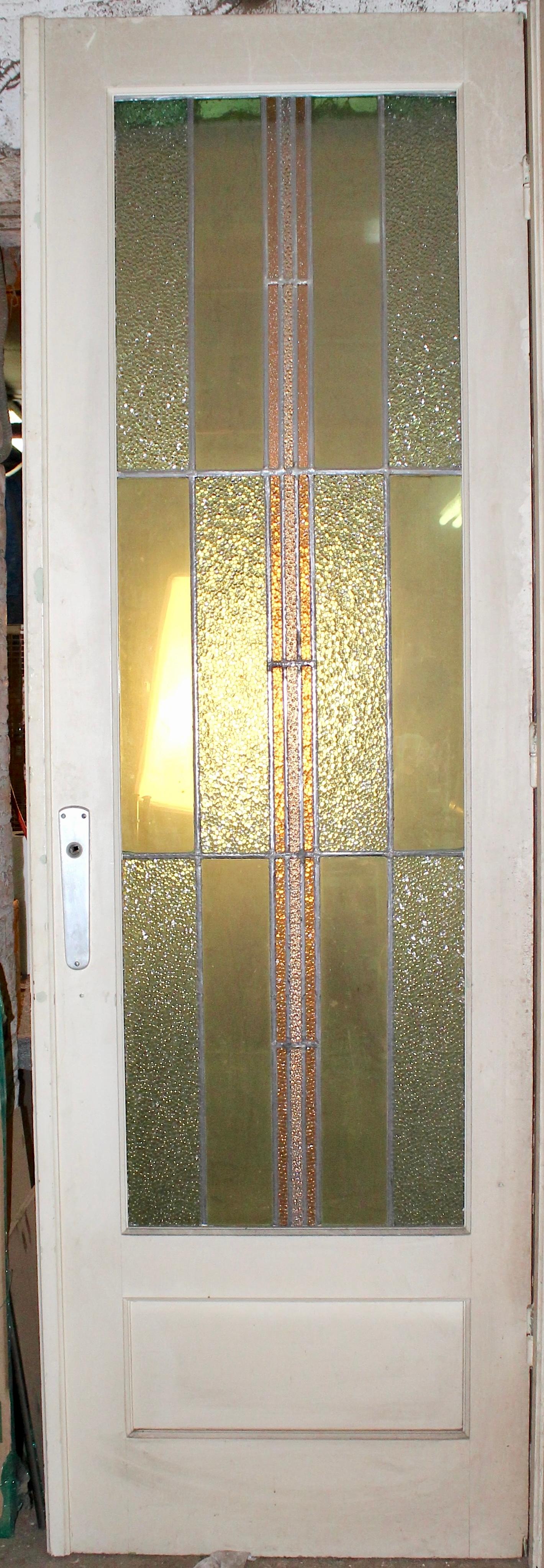 Questa porta alta più di 3 metri è dotata di una lunga vetrata in vetro colorato. Un design semplice in stile Art Deco con vetro testurizzato per garantire la privacy.