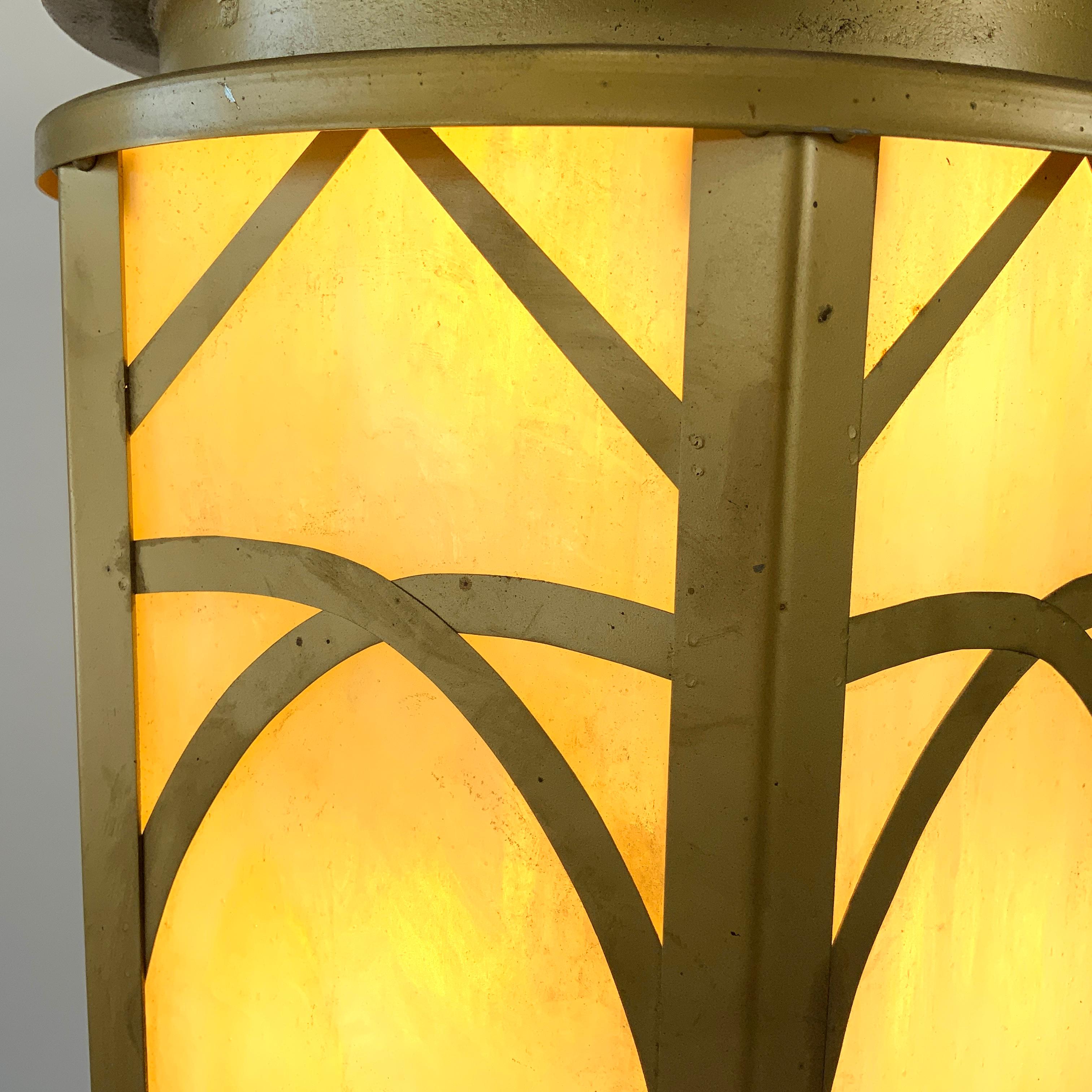 A pair of unusual six-sided (hexagonal) cathedral lantern lamps, the main frame in sheet metal and the crown in 0.25 in. cast iron. The stained glass is a mottled cream-light yellow slag glass. Besides the typical Art Deco interweaving metal design,