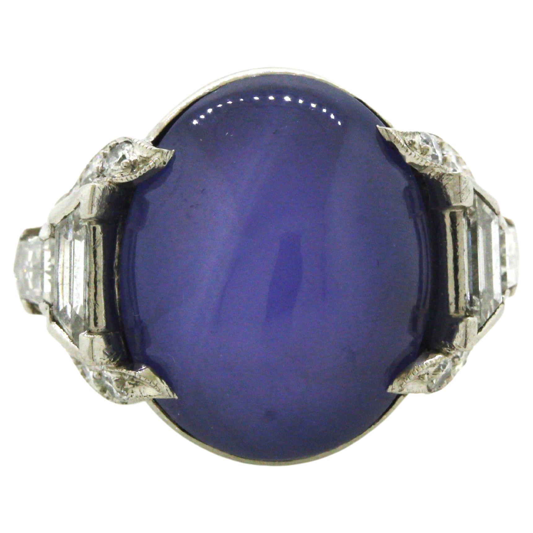 A beautiful Art Deco platinum ring made in the late 1920s. It features a blue star sapphire, weighing approximately 15 carats, which has a rich even violetish-blue color. It is complemented by 0.75 carats of bright white diamonds set on the sides of