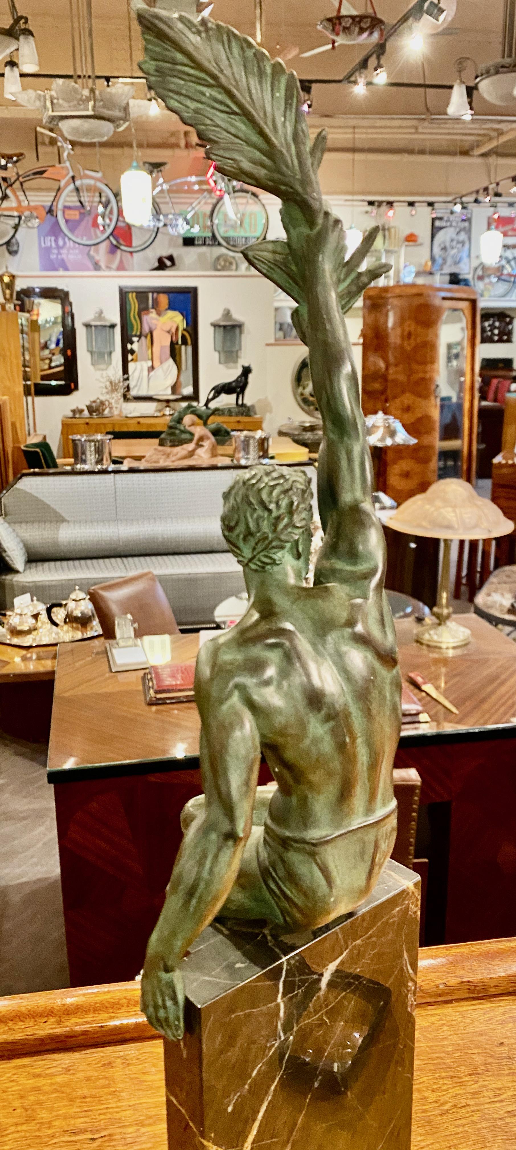 An original French Art Deco sculpture of a triumphant male wearing a loin cloth, known as “Gloire” by Pierre Le Faguays (active in France, born 1892 – died 1962). This piece dates circa 1920-1930. The figure sits on top of a tall black marble