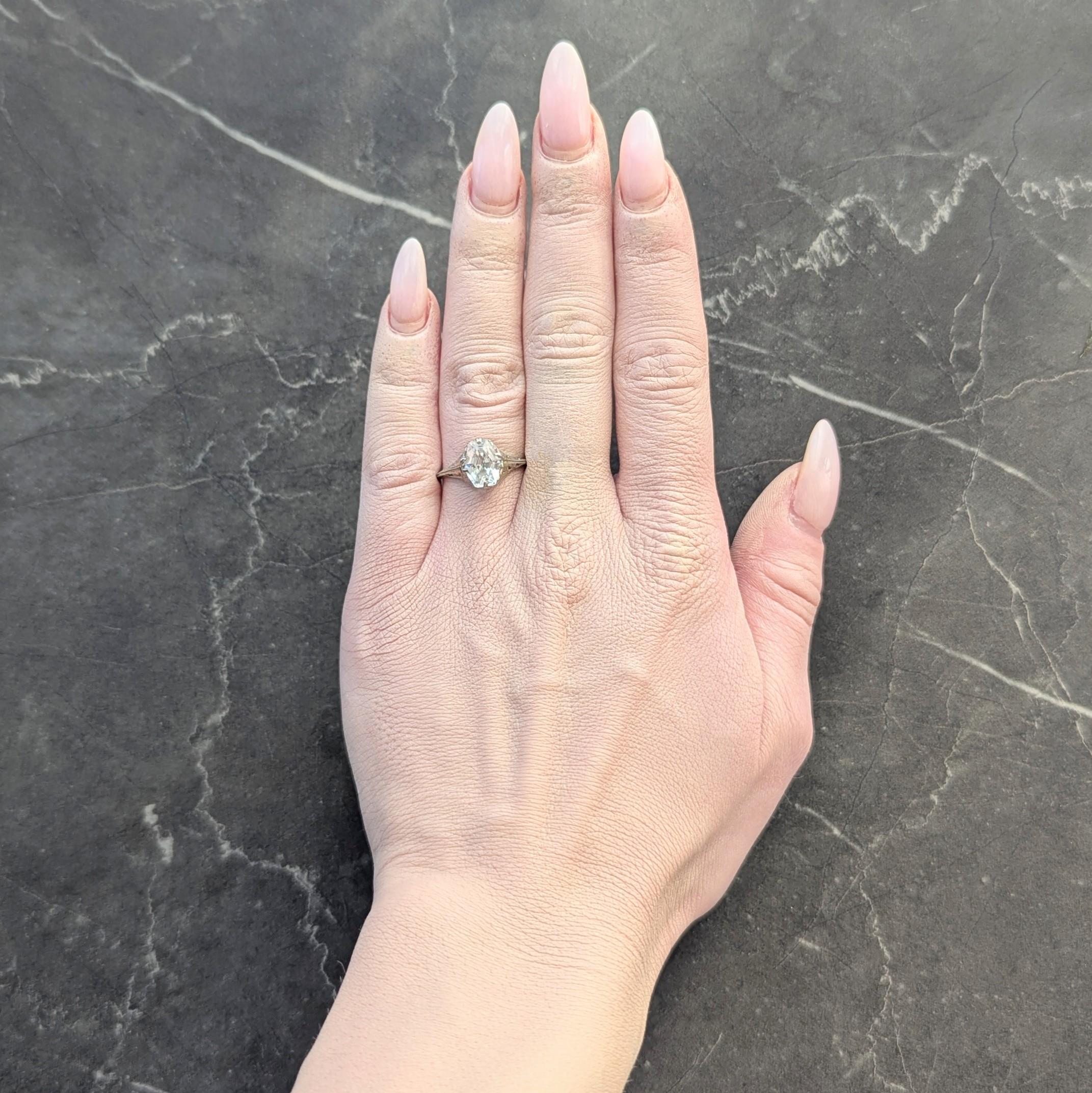 Centering a hexagonal shaped step-cut grossularite garnet weighing approximately 2.18 carats
Transparent very very light blue in color - near colorless
Set with split talon and tab-like prongs
With a pierced foliate motif gallery
Flanked by grooved