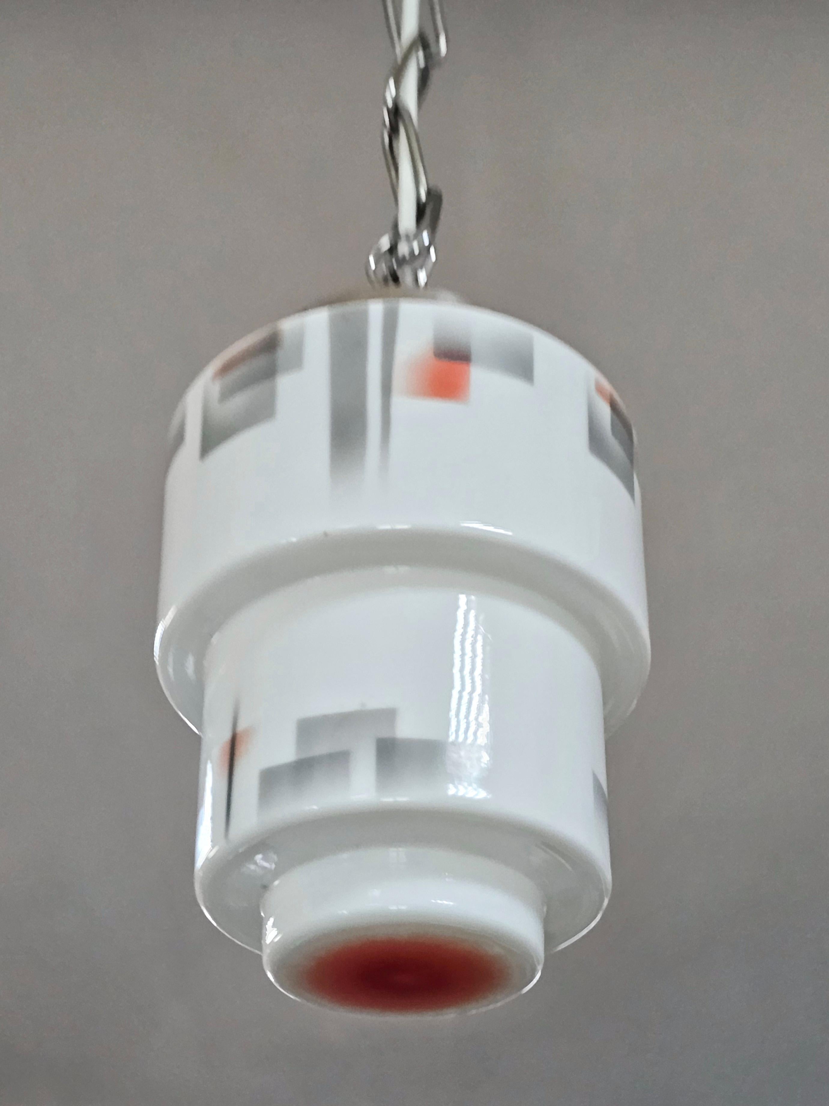 In this listing you will find a beautiful, small Stepped Skyscraper Art Deco pendant light. The glass shade is done in white opaline glass, with gray and red print on it, making it a perfect combination of colors. Perfect choice for the small