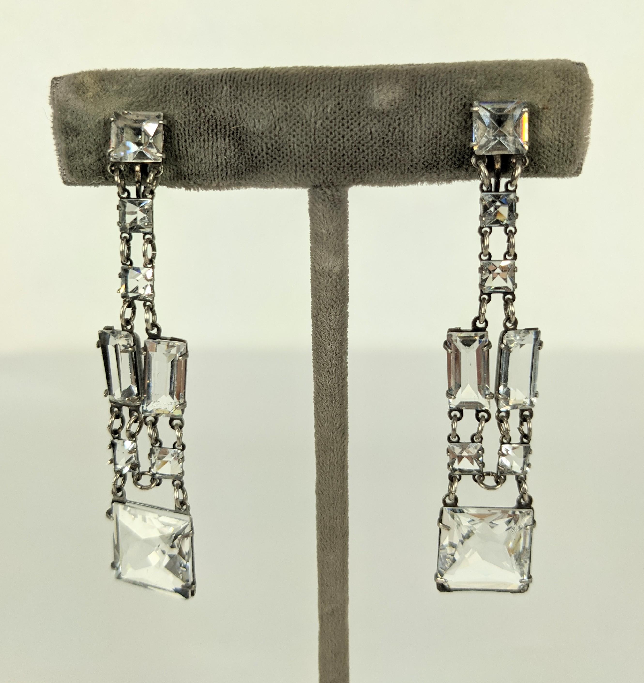 Attraktive Art-Déco-Ohrringe aus Sterling-Kristallpaste mit Schraubverschluss. Quadratische und Baguette-Steine in Bleikristall sind in einem flexiblen Deco-Muster mit winzigen Sprungringen verbunden.  
1920er Jahre USA.  2.5
